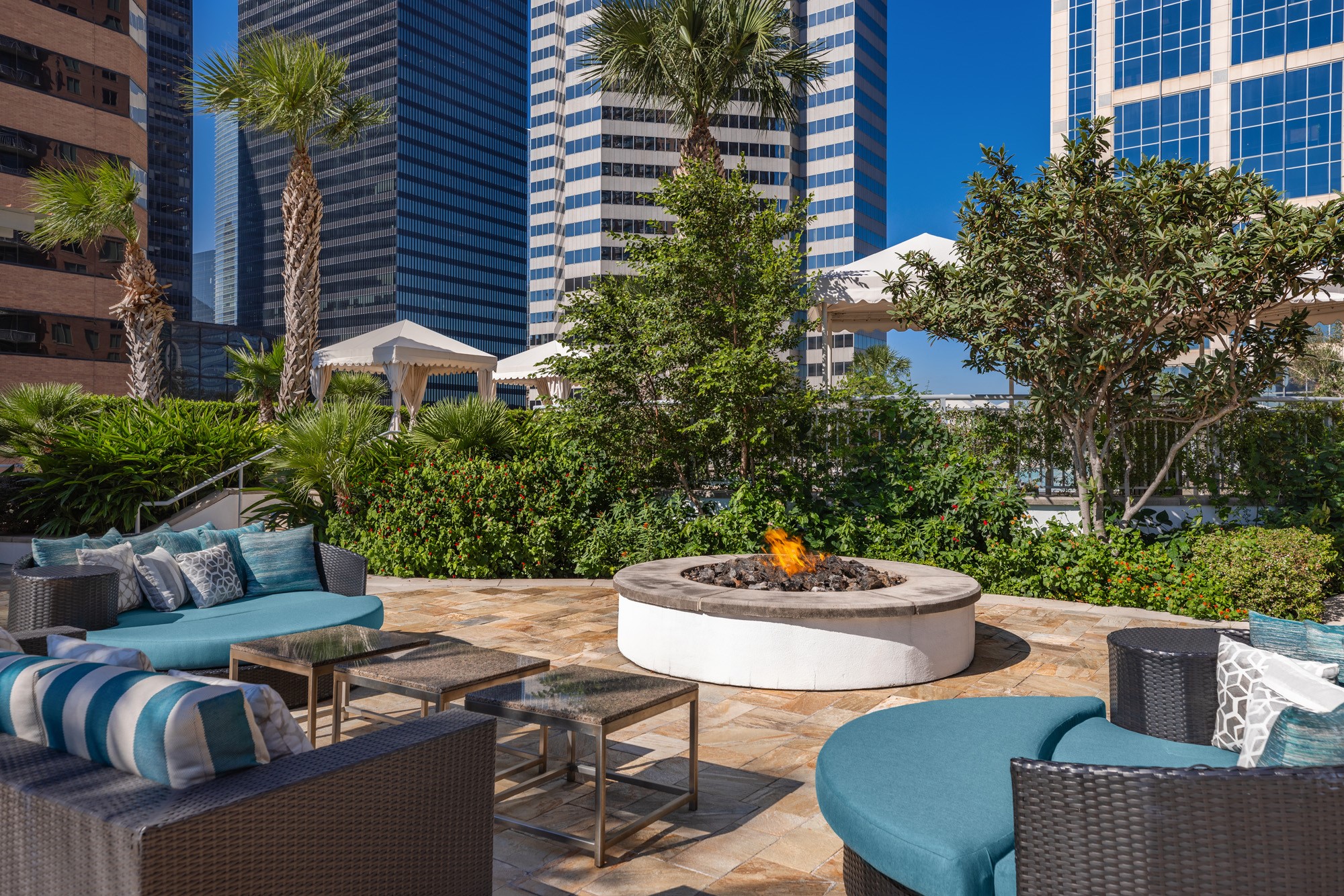 Enjoy evenings under the stars in the beautifully appointed outdoor lounge, featuring a cozy fire pit, plush seating and lush landscaping. Designed for conversation and relaxation, this elegant gathering space offers a true resort-inspired experience.