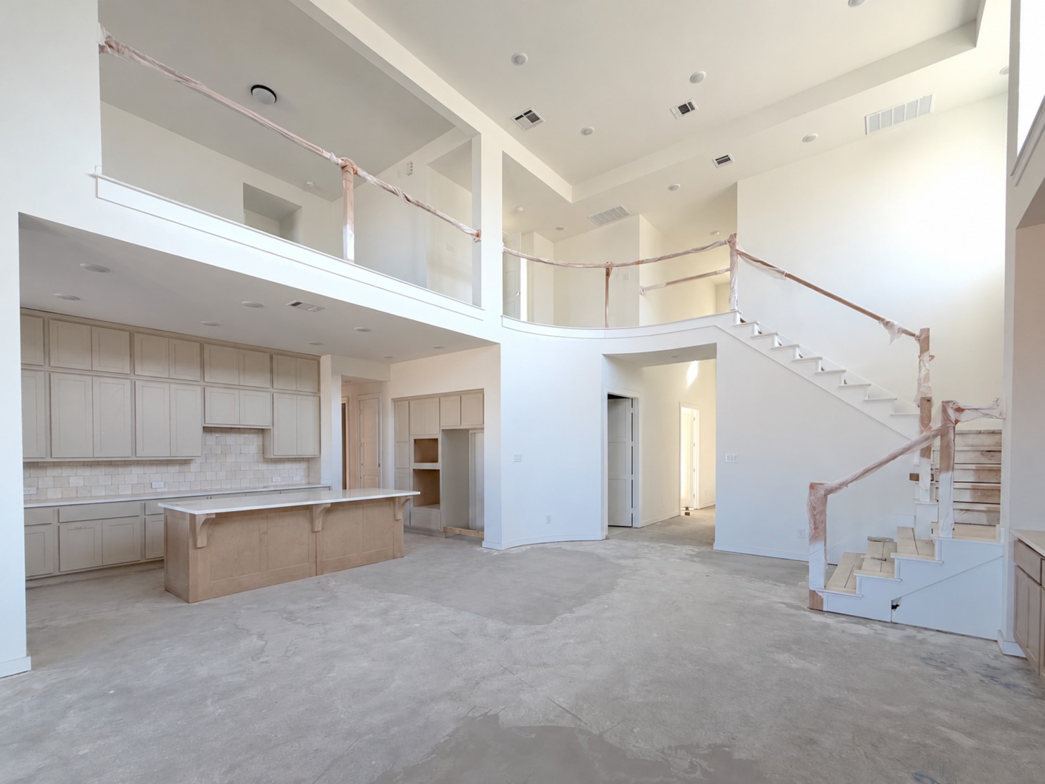 Expansive open concept living area featuring soaring ceilings, a dramatic staircase, and a curved open to below
