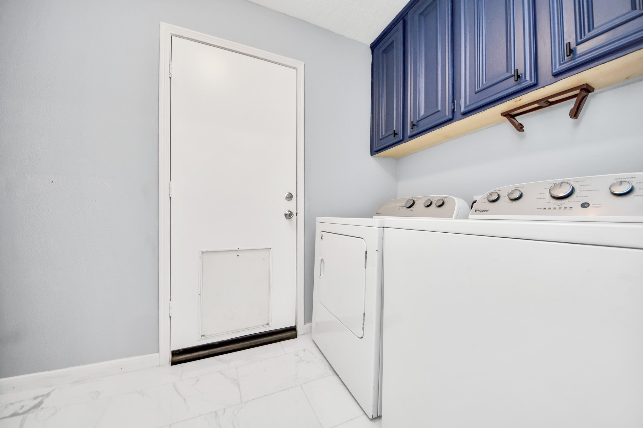 This high-utility space keeps chore day organized with a vibrant row of cool blue overhead cabinetry positioned perfectly above the washer and dryer hookups.