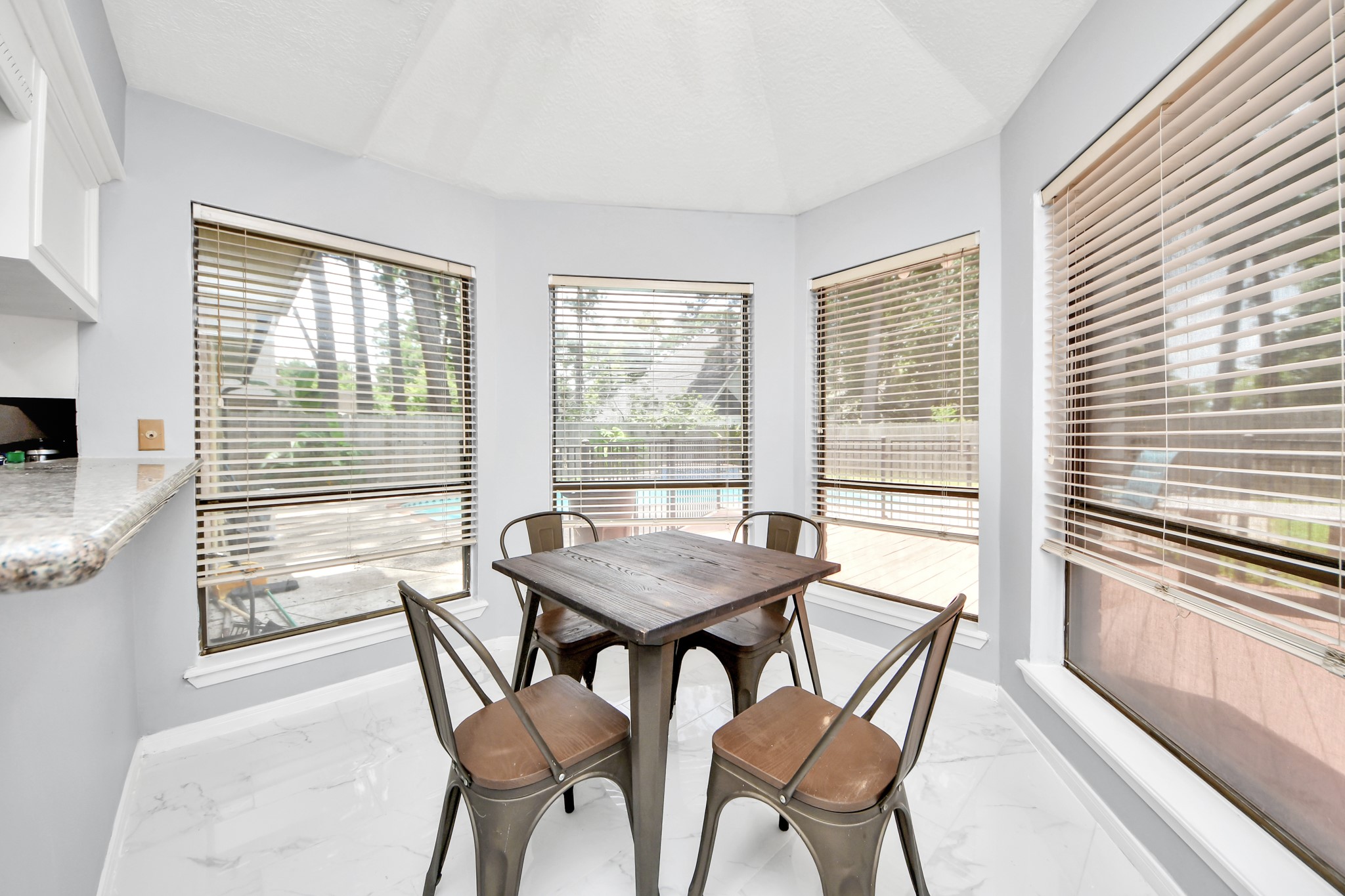 Sun-drenched morning perfection. Wrapped in a bank of oversized windows, this cheerful casual dining space offers panoramic, uninterrupted views of the sparkling pool area outside.