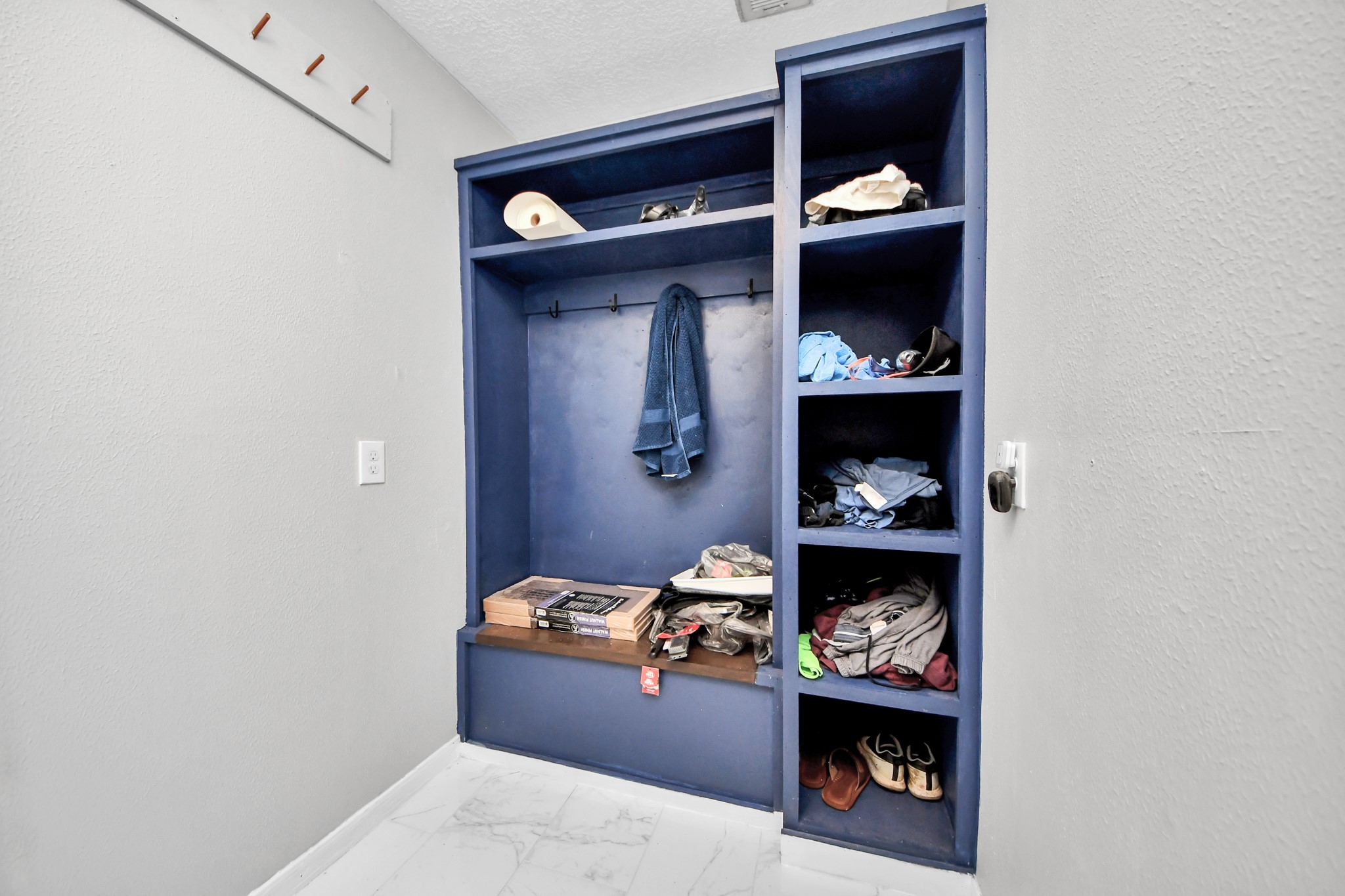 Seamless daily transitions. Continuing the sophisticated blue aesthetic, this dedicated drop-zone is thoughtfully outfitted with hanging coat hooks and integrated storage cubbies.