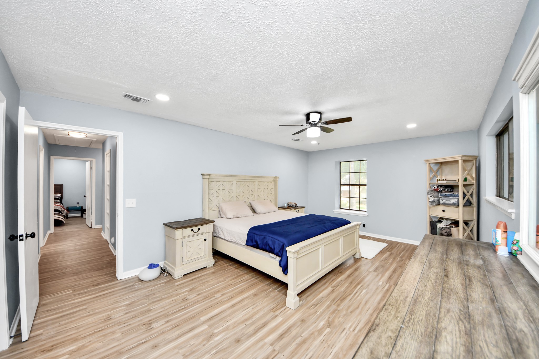 Located for premium seclusion, this spacious primary bedroom pairs a cooling ceiling fan with broad windows that bathe the room in peaceful morning light.