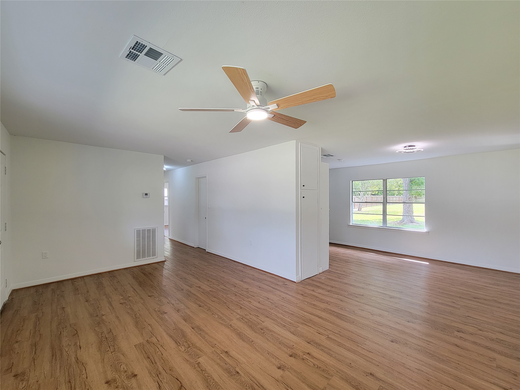Discover a spacious living area with elegant wood flooring, abundant natural light from large windows, and a modern ceiling fan for ultimate comfort. Discover a spacious living area with elegant wood flooring, abundant natural light from large windows, and a modern ceiling fan for ultimate comfort.
