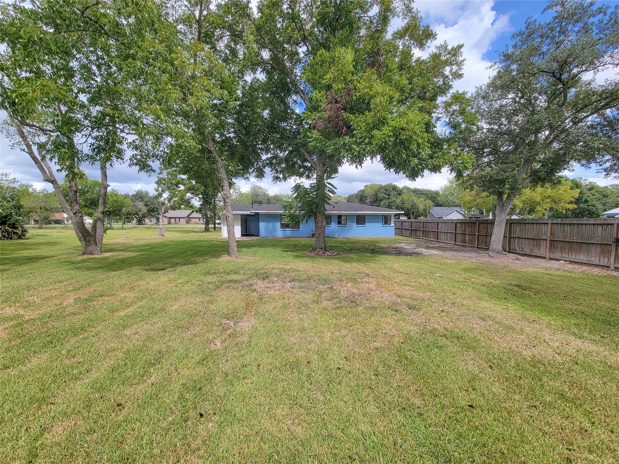 Discover a serene oasis with an expansive backyard featuring a lush green lawn and mature trees, perfect for outdoor activities and relaxation.
