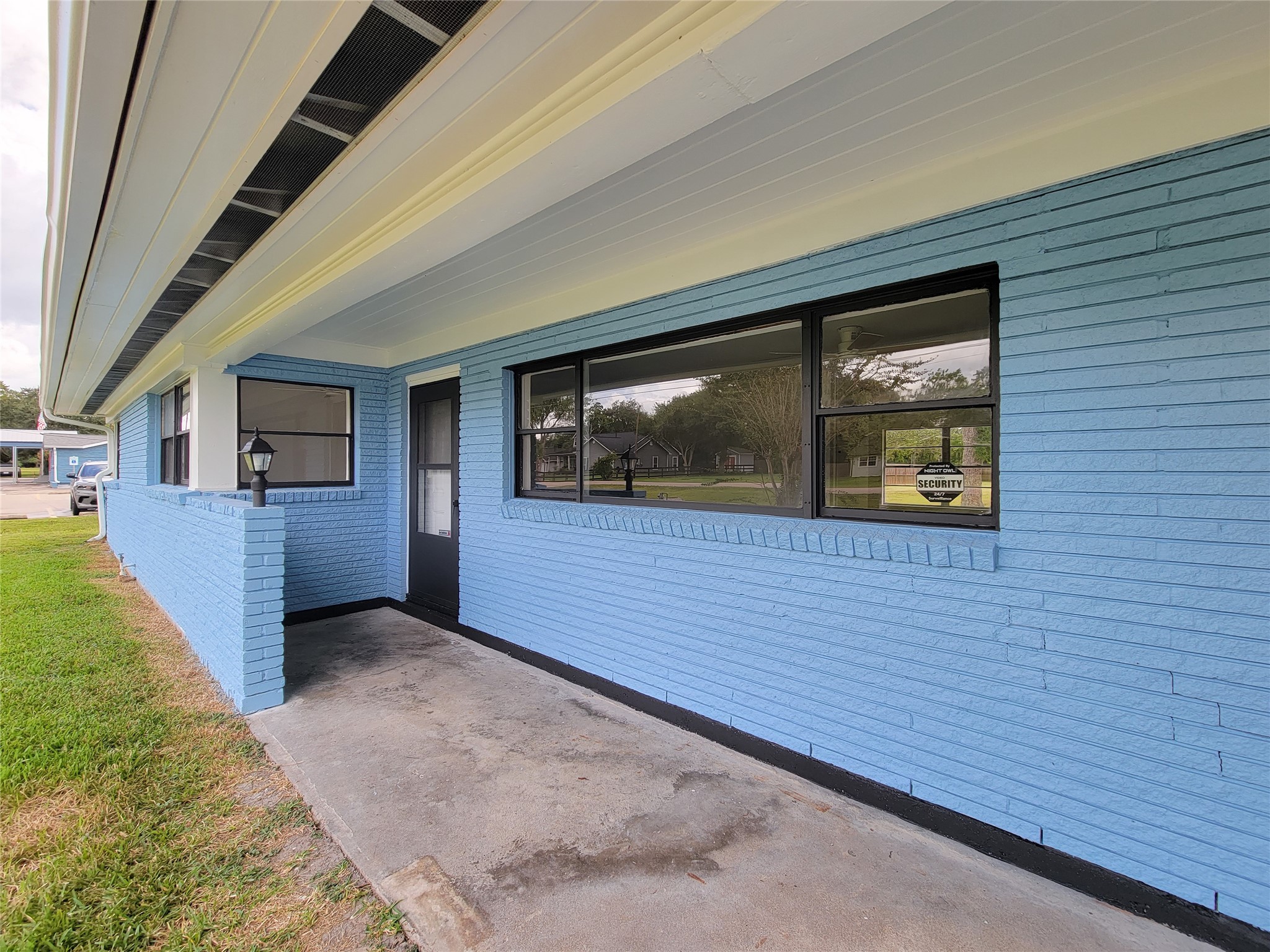 Charming blue brick exterior with a welcoming covered front porch and large windows, ideal for enjoying the outdoors.