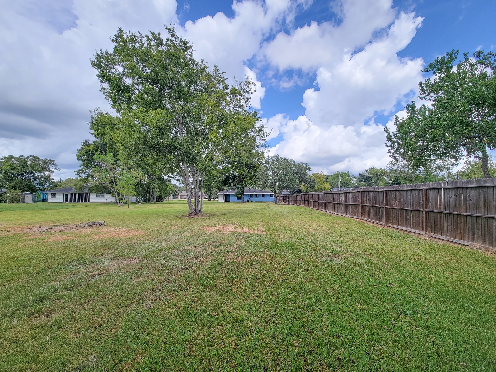 Discover an expansive, lush backyard with mature trees and a privacy fence, perfect for outdoor activities and tranquil relaxation.