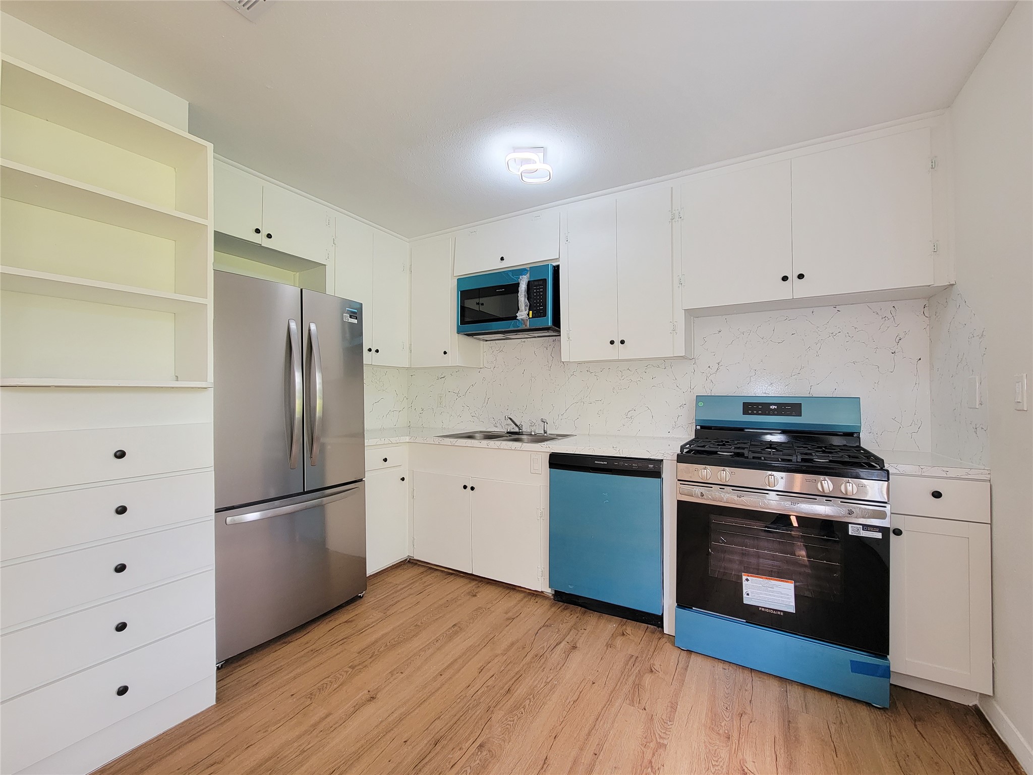 Discover the perfect blend of modern elegance with sleek stainless steel appliances, ample white cabinetry, and stylish wood flooring in this contemporary kitchen.