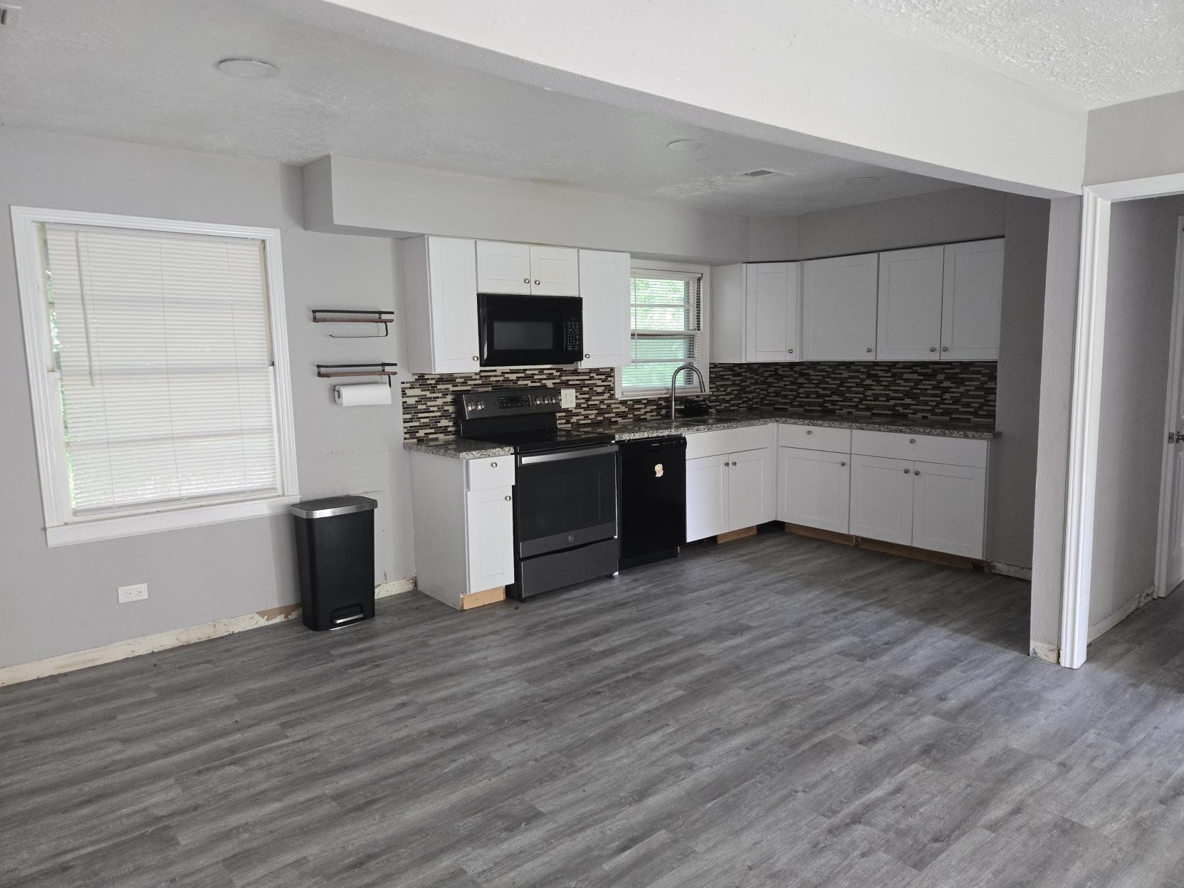 A modern kitchen with, cabinets, appliances, and a laminate floor.