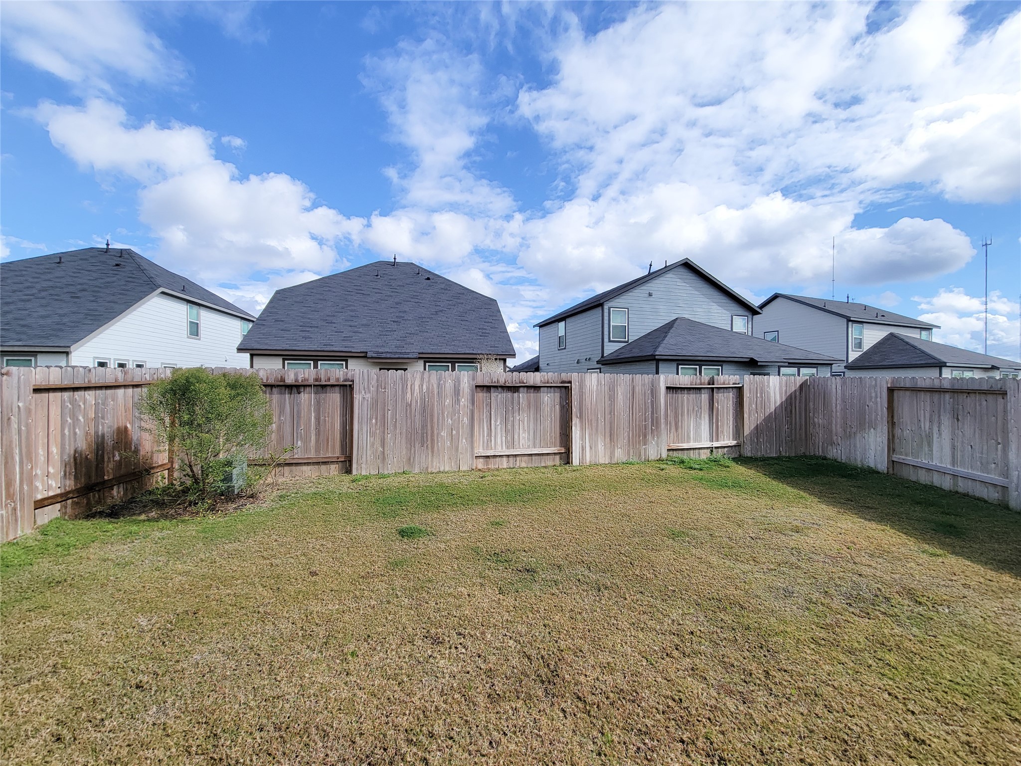 Spacious fenced backyard with a well-maintained lawn, offering privacy and potential for landscaping or outdoor activities.