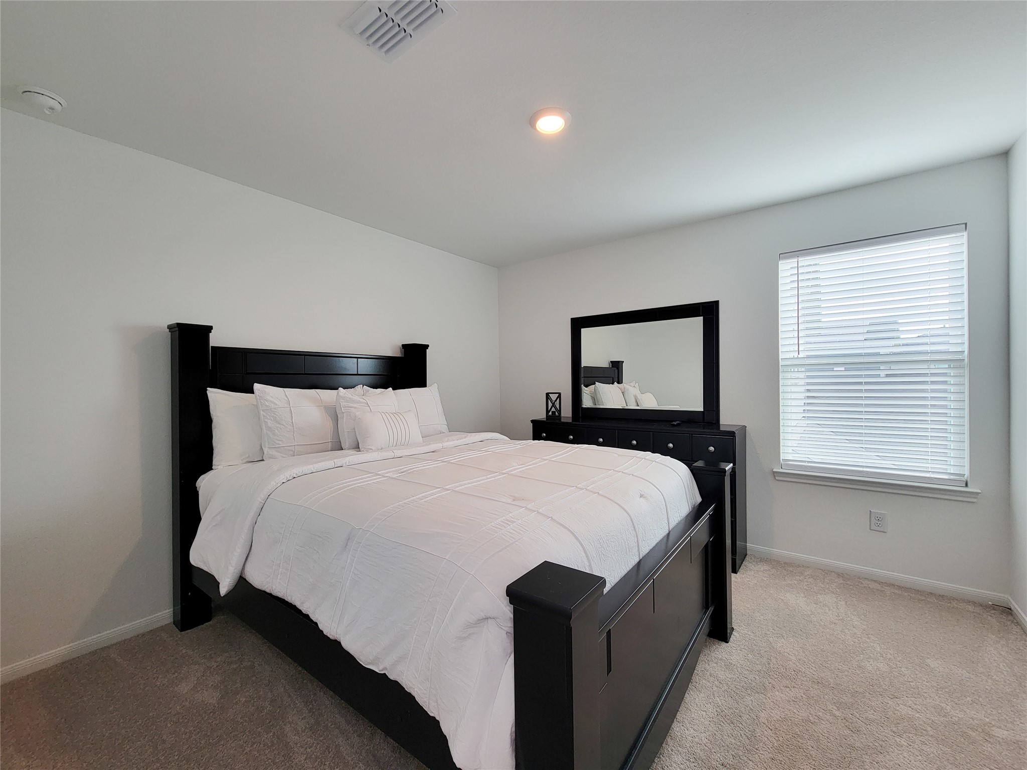 Cozy bedroom featuring. Natural light fills the room through a window with blinds, creating a bright and inviting atmosphere.