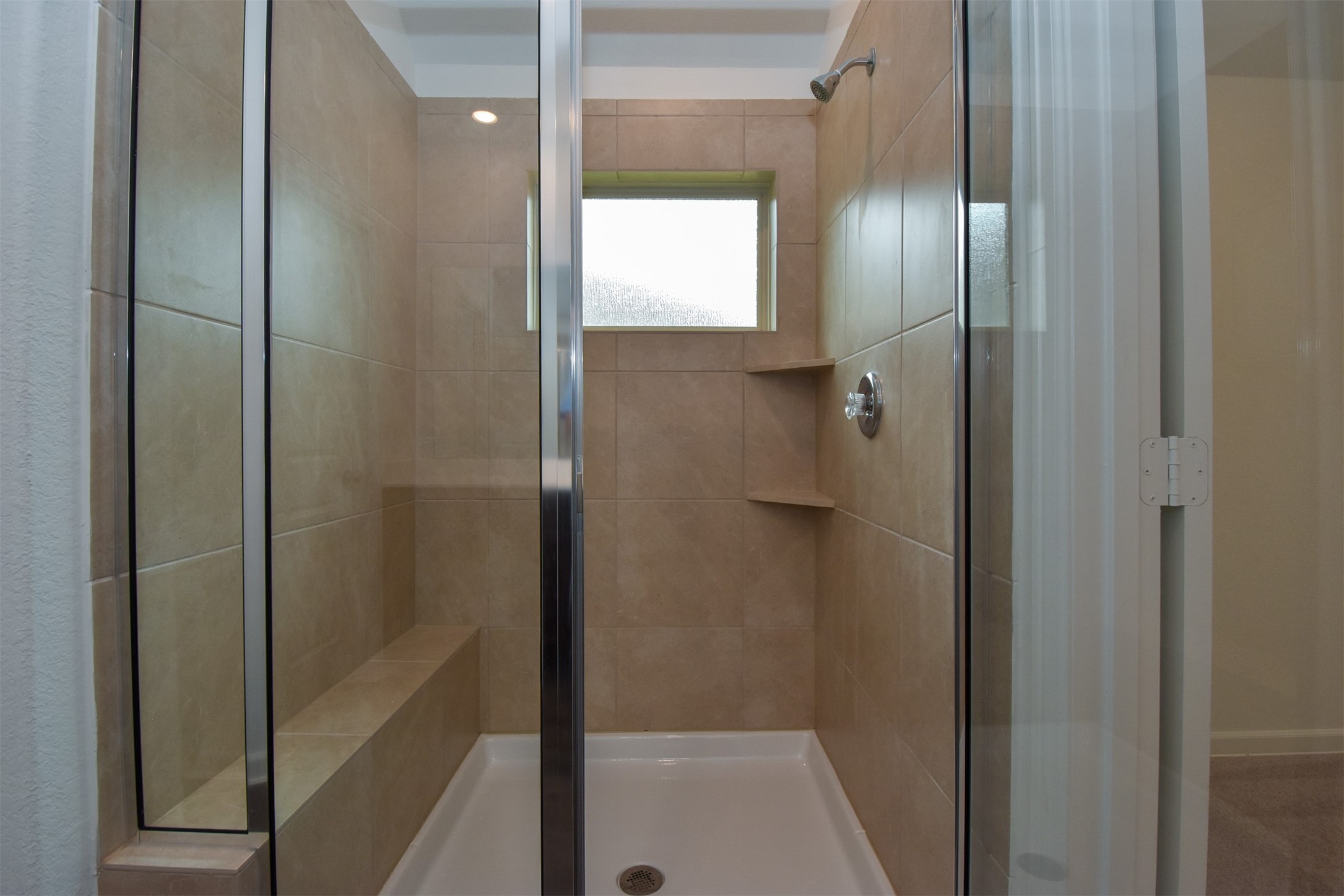 Large stand up shower with built in seating and shear glass door