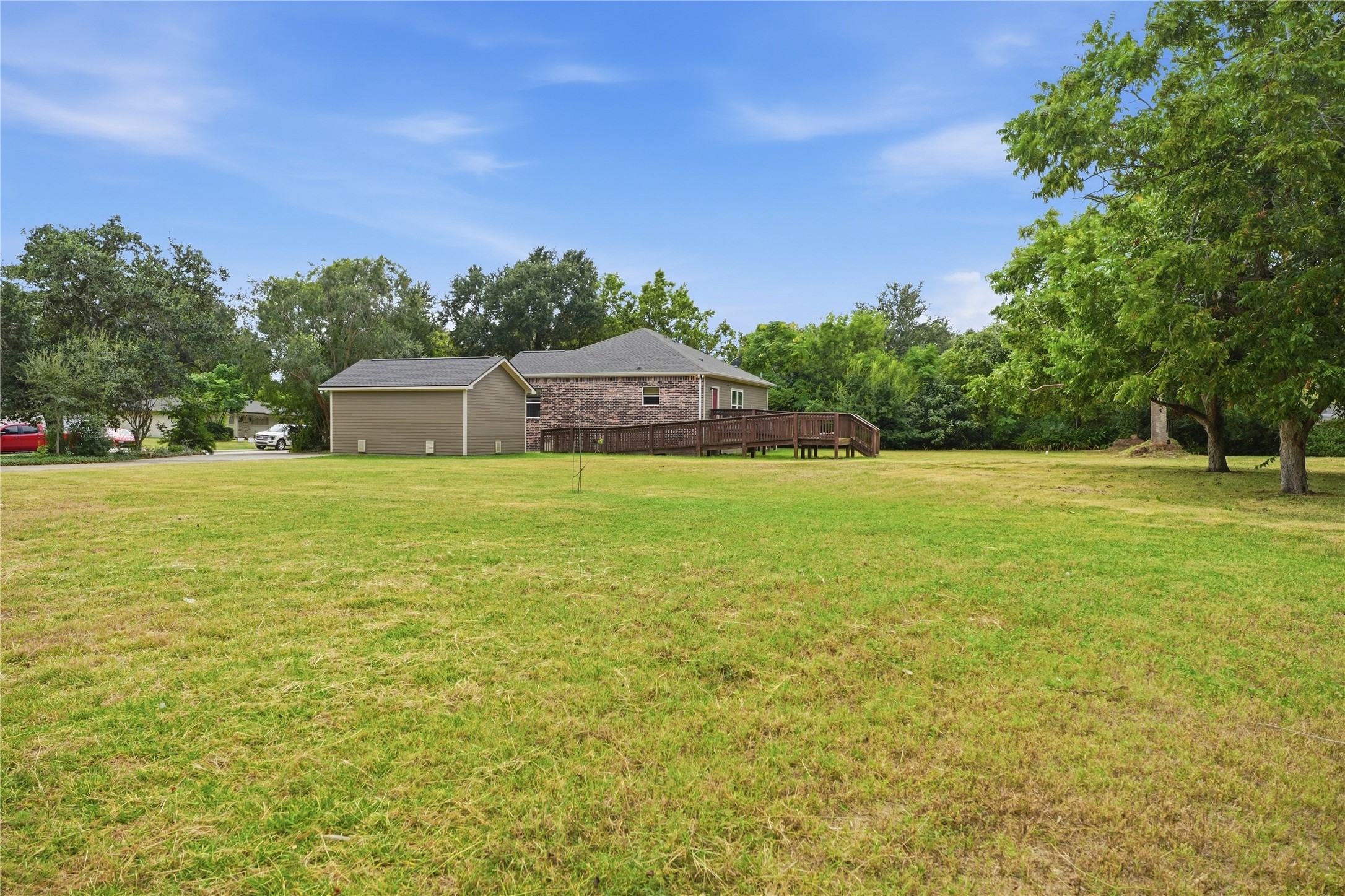 A wide view of the yard shows the home, detached garage, and access ramp leading to the back entrance.