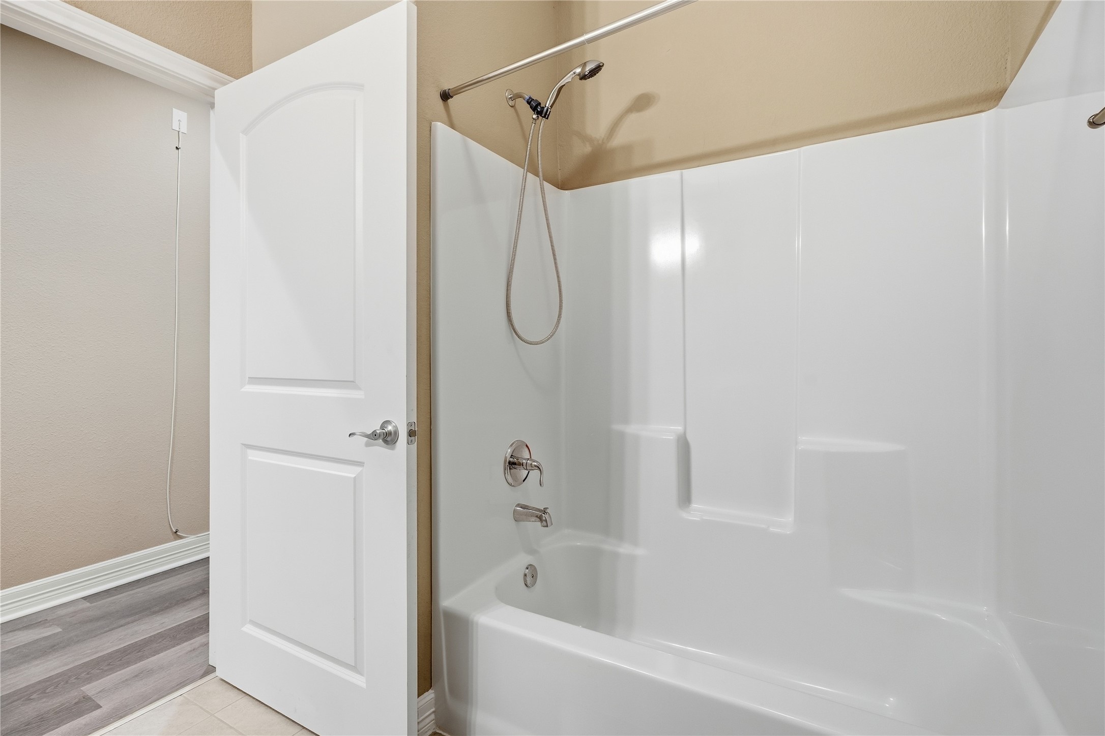 A tub and shower combination with a handheld showerhead and built-in shelves for bath essentials.