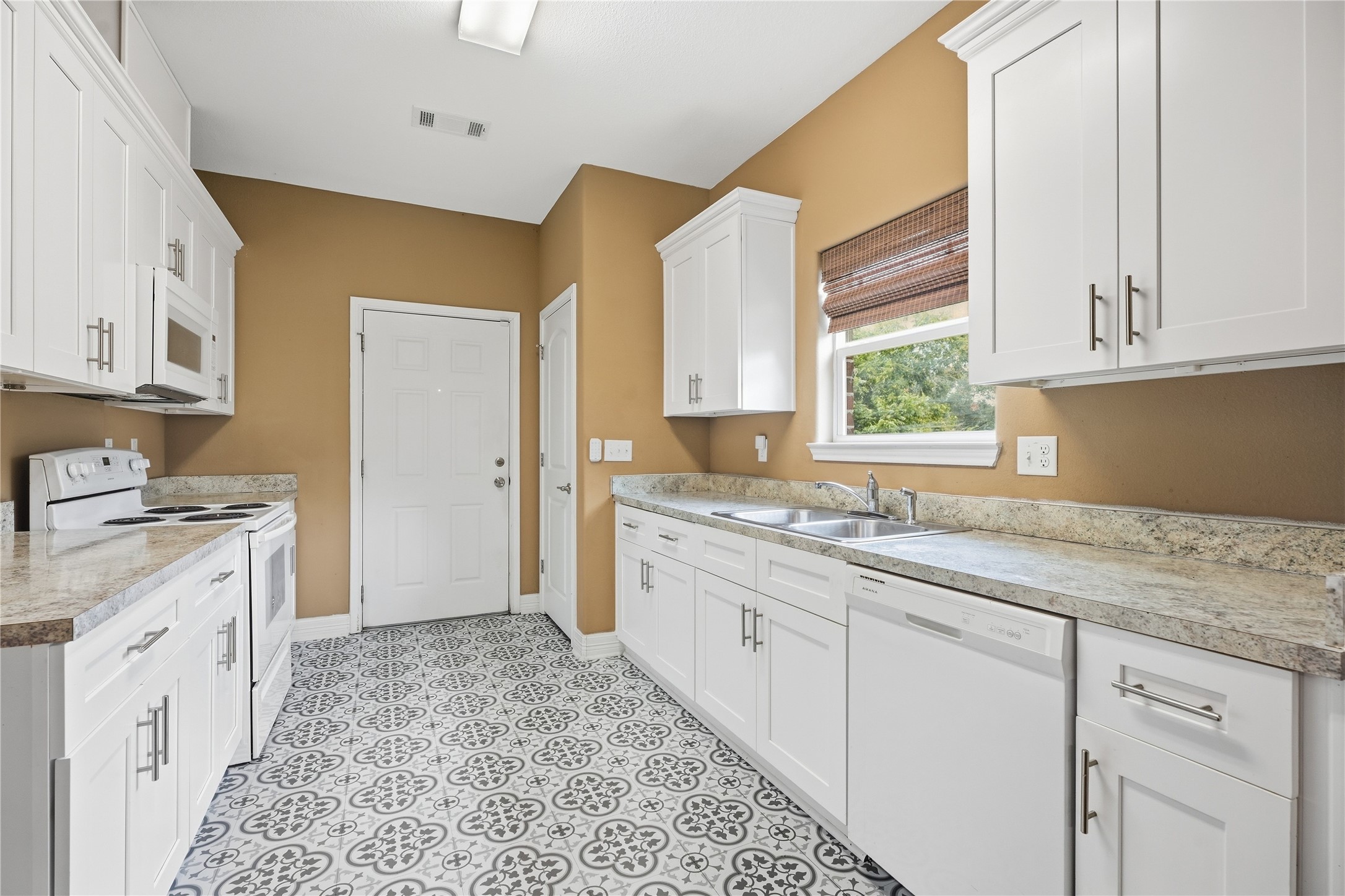 A window above the double sink brings in natural light and a view of the yard, with the dishwasher conveniently beside it.