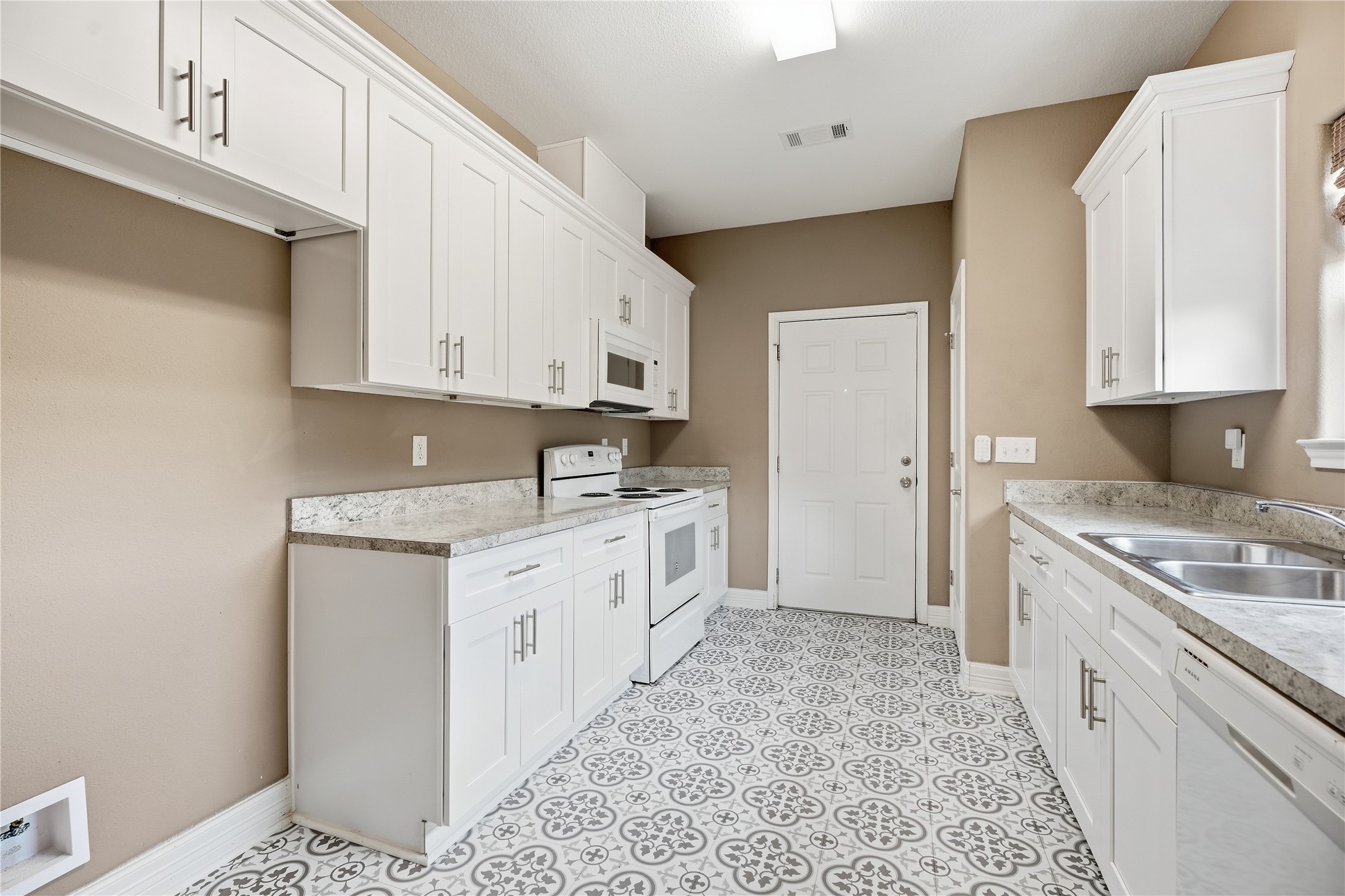 The kitchens galley layout keeps everything within reach, with an electric range, overhead microwave, and cabinets on both sides.