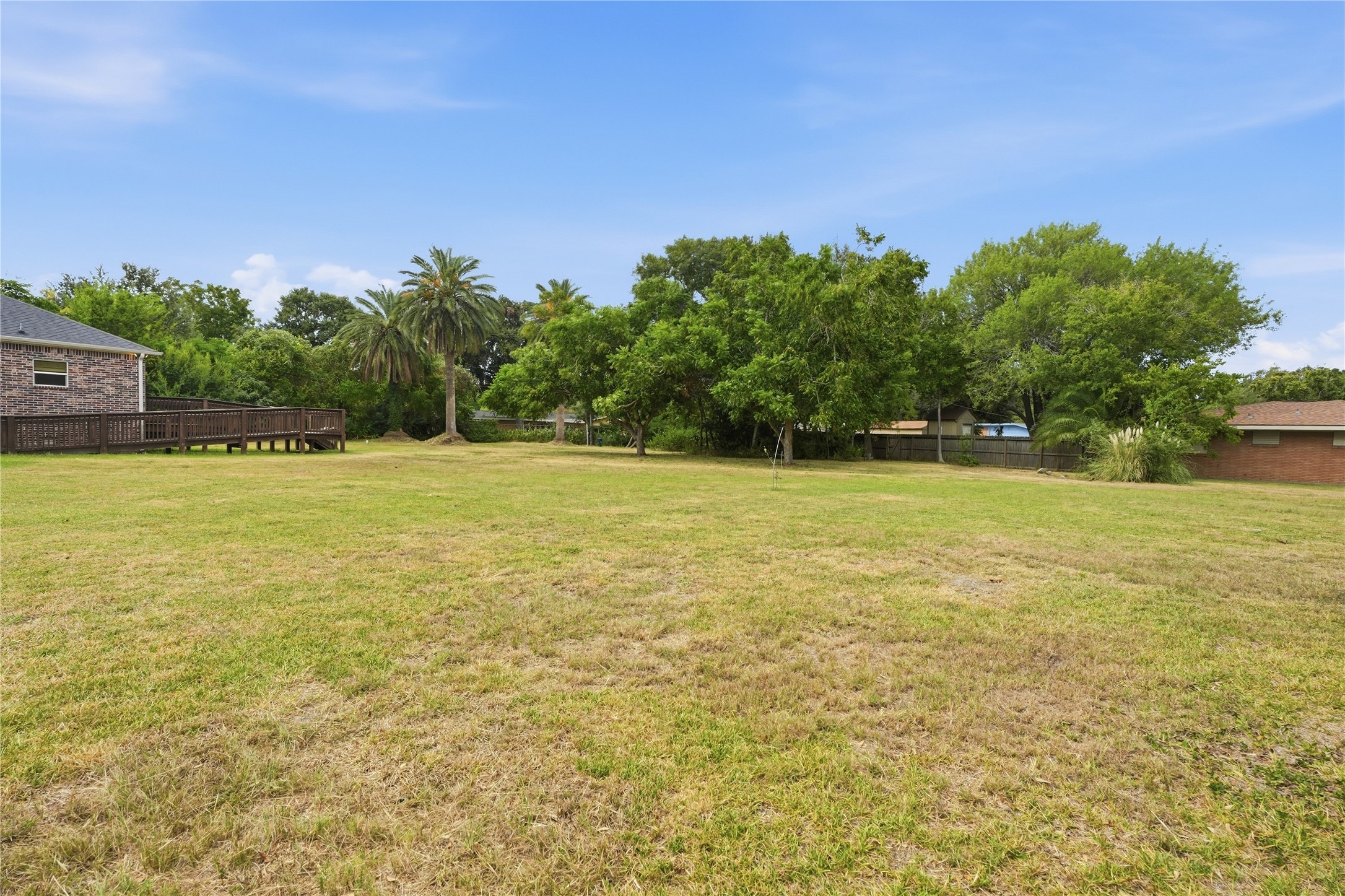 Mature trees and palms surround the spacious yard, with room for a garden, outdoor games, or a shaded seating area.