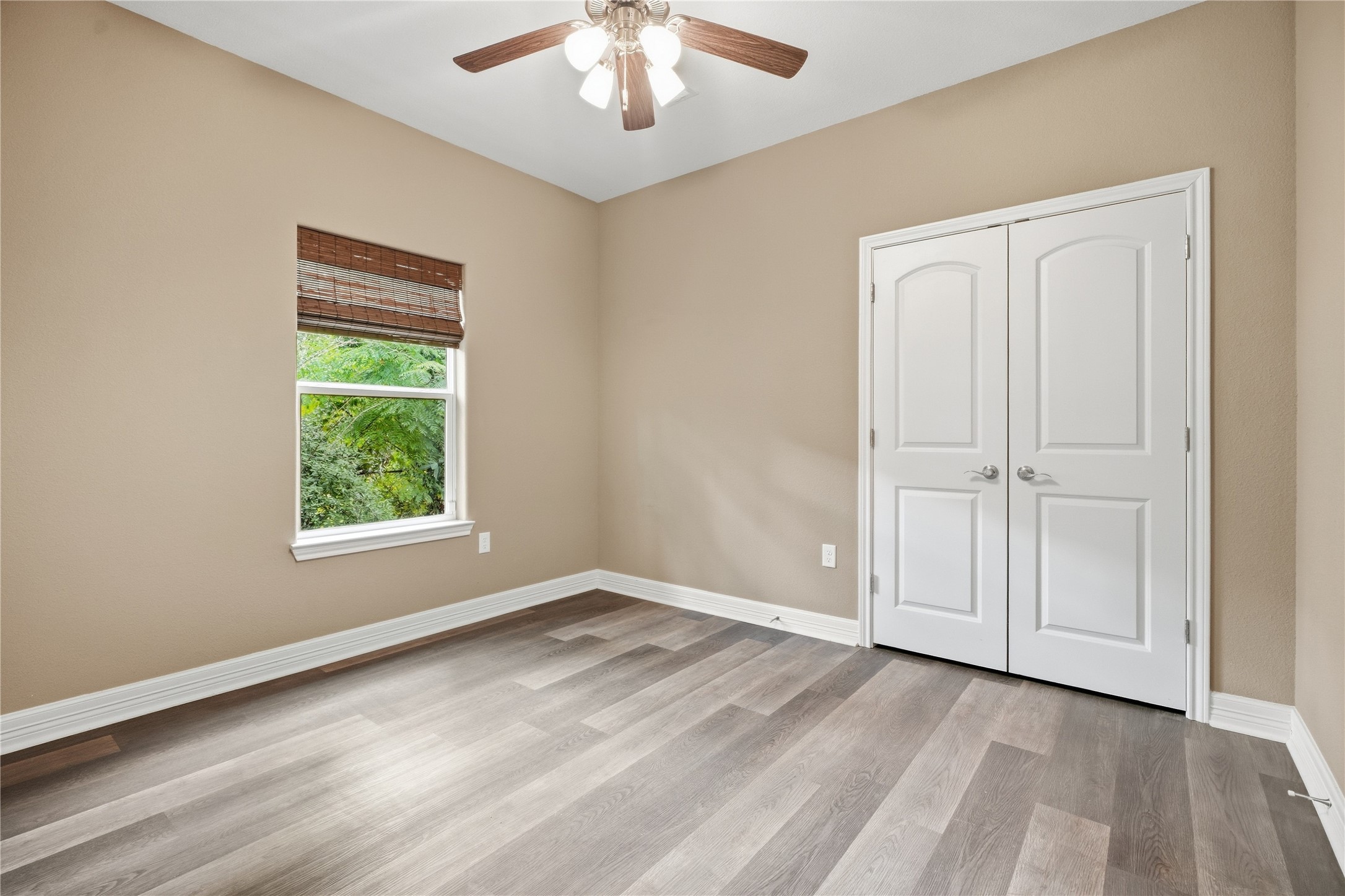 This secondary bedroom features a double-door closet, ceiling fan, and a window overlooking the trees. Use it as a bedroom, guest room, or home office.