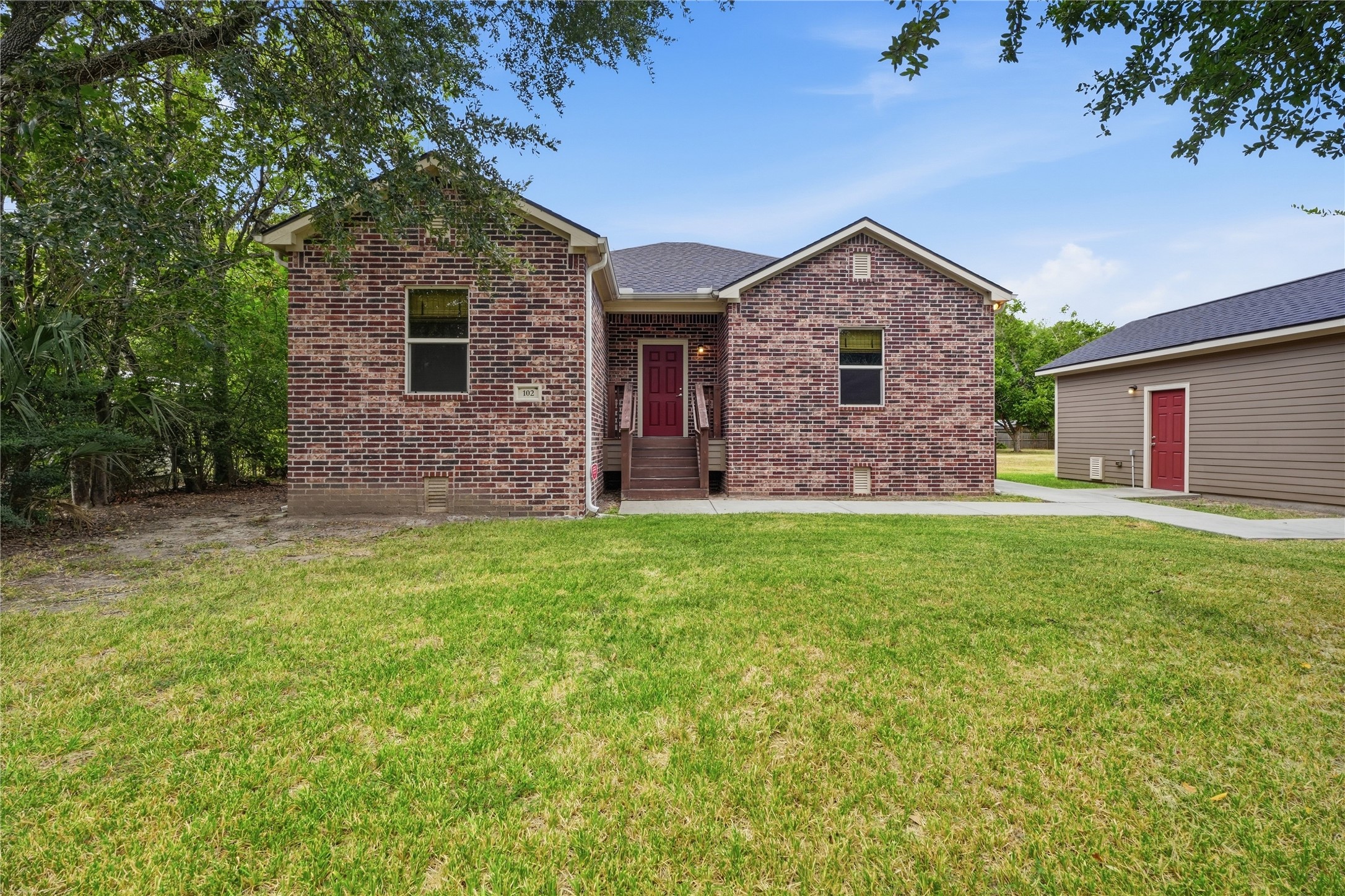 Brick exterior with a covered front entry and mature trees that add shade to the front yard.