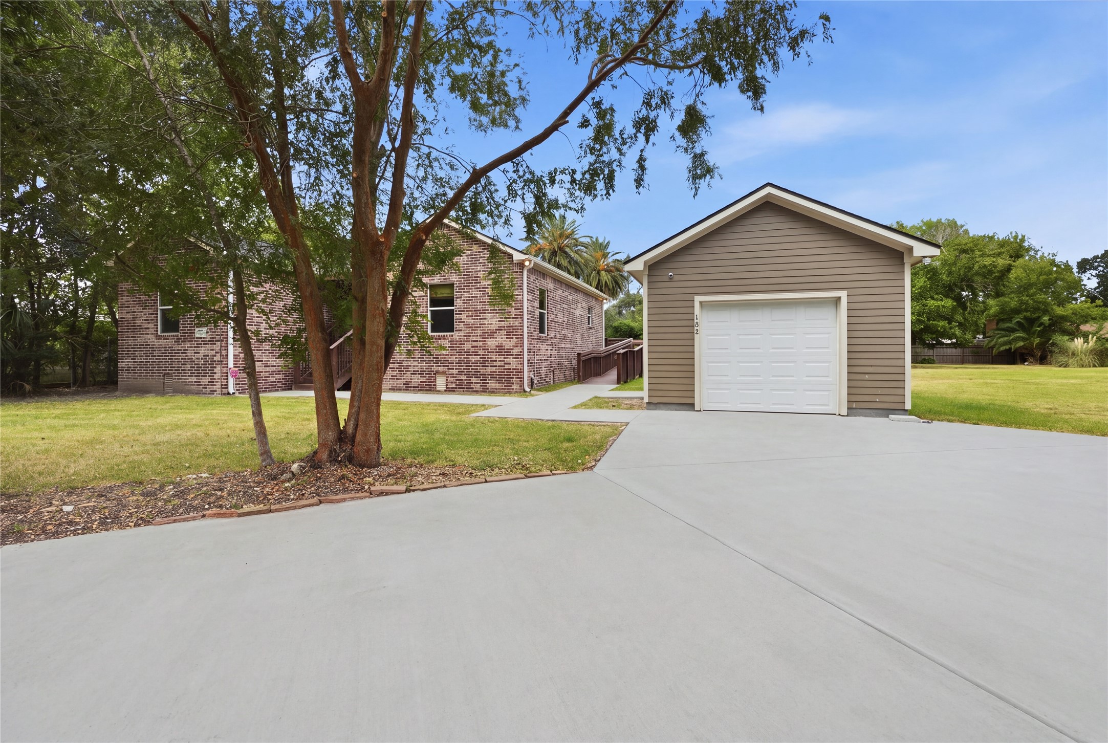 Detached garage with a wide circle concrete driveway offering additional parking. A walkway leads to the homes side access ramp.