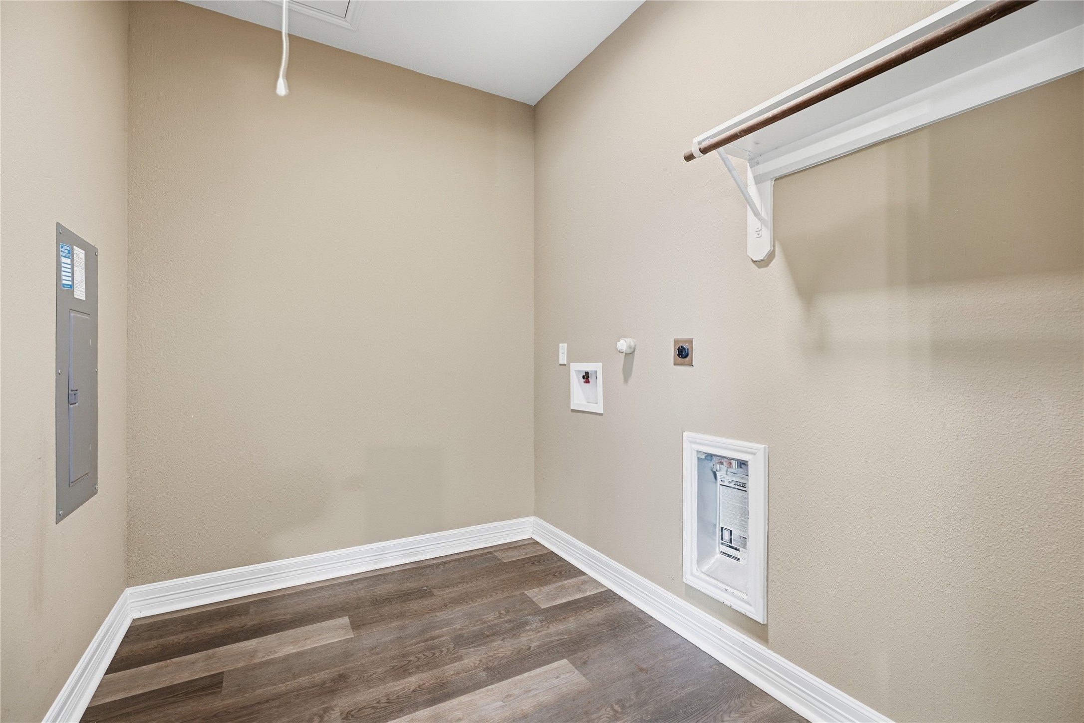 Indoor laundry room with washer and dryer connections, an overhead shelf, and a hanging rod to keep laundry organized.