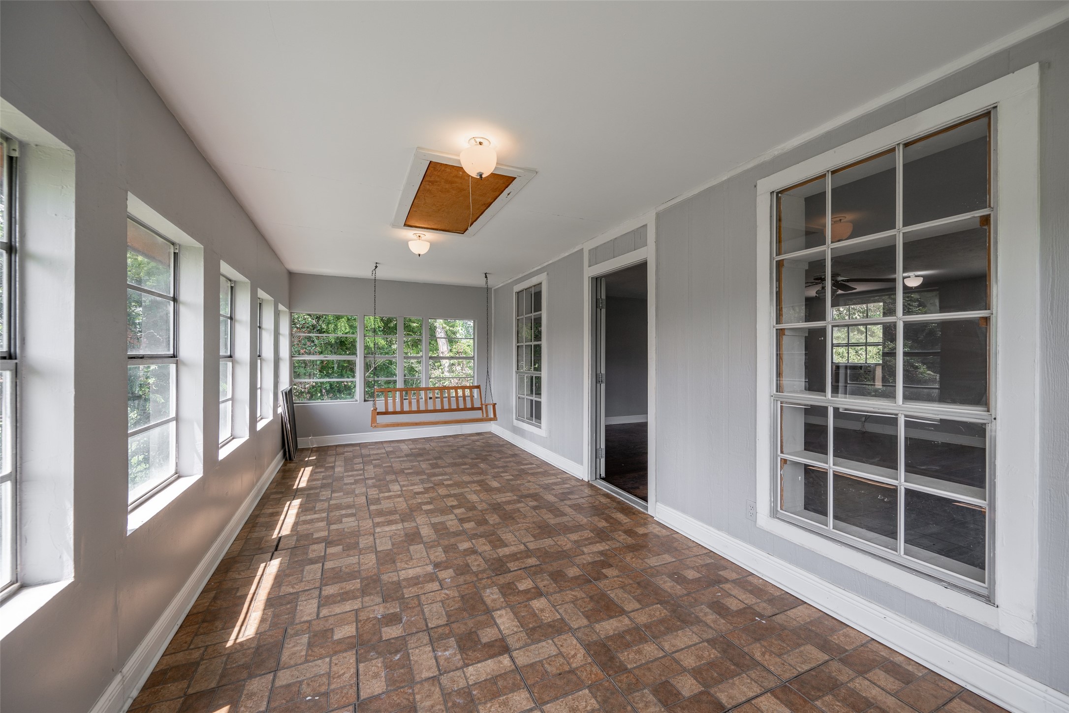 Experience abundant natural light in this inviting sunroom, featuring elegant flooring and a stylish chandelierperfect for relaxation or entertaining.