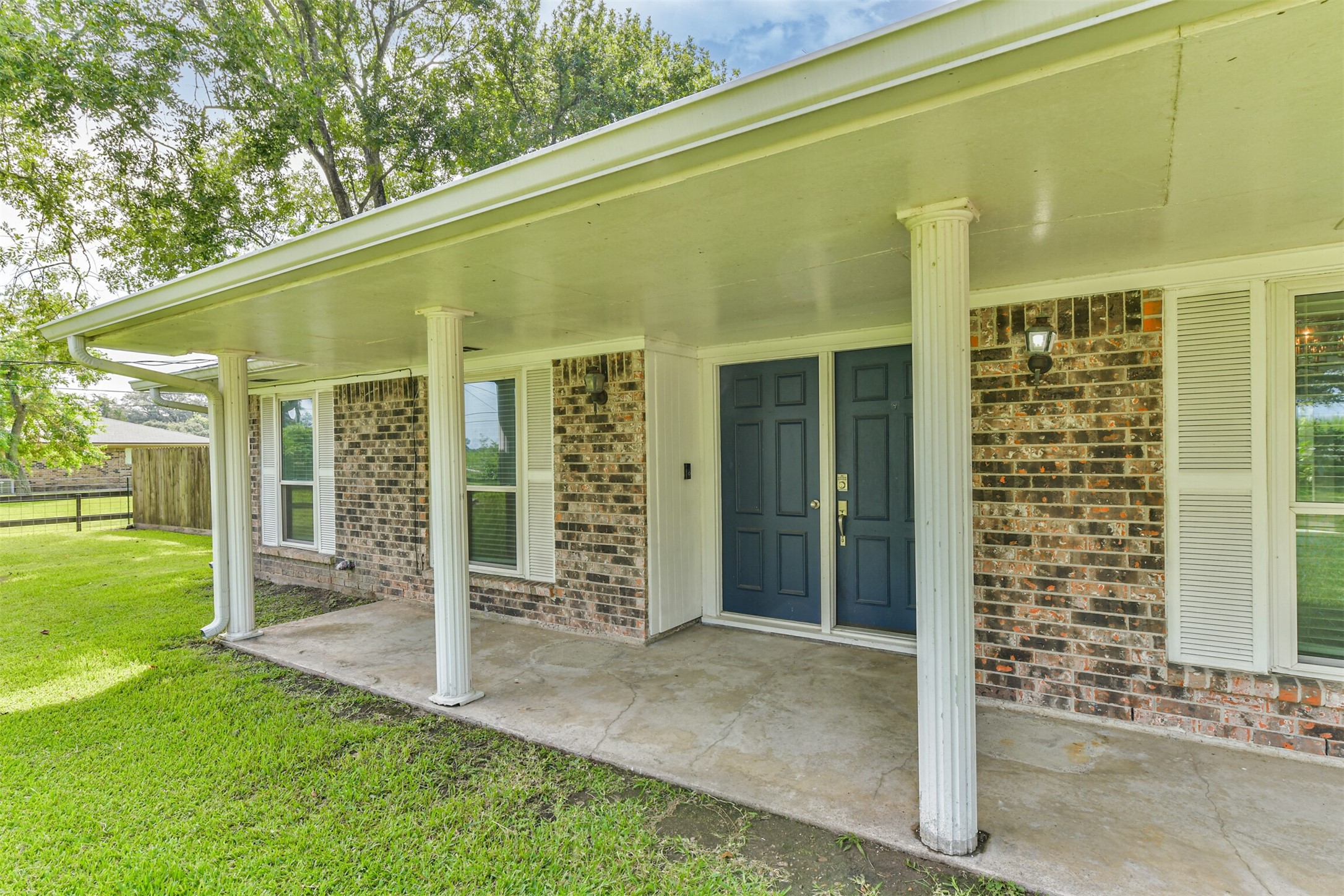 Welcoming front porch with classic columns and a serene view, perfect for relaxing afternoons.