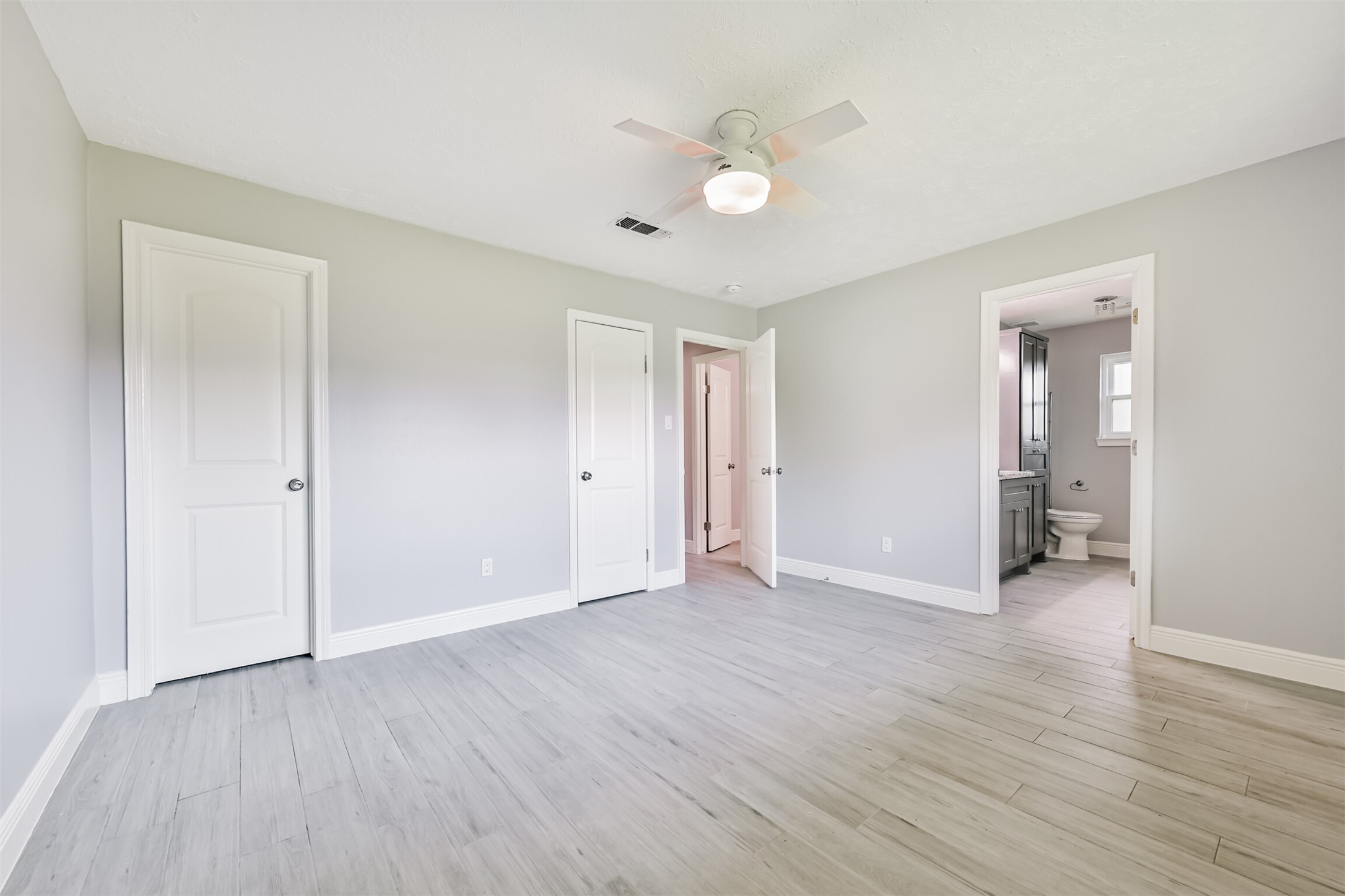 Spacious primary bedroom with modern flooring, ample natural light, and an en-suite bathroom for ultimate comfort.