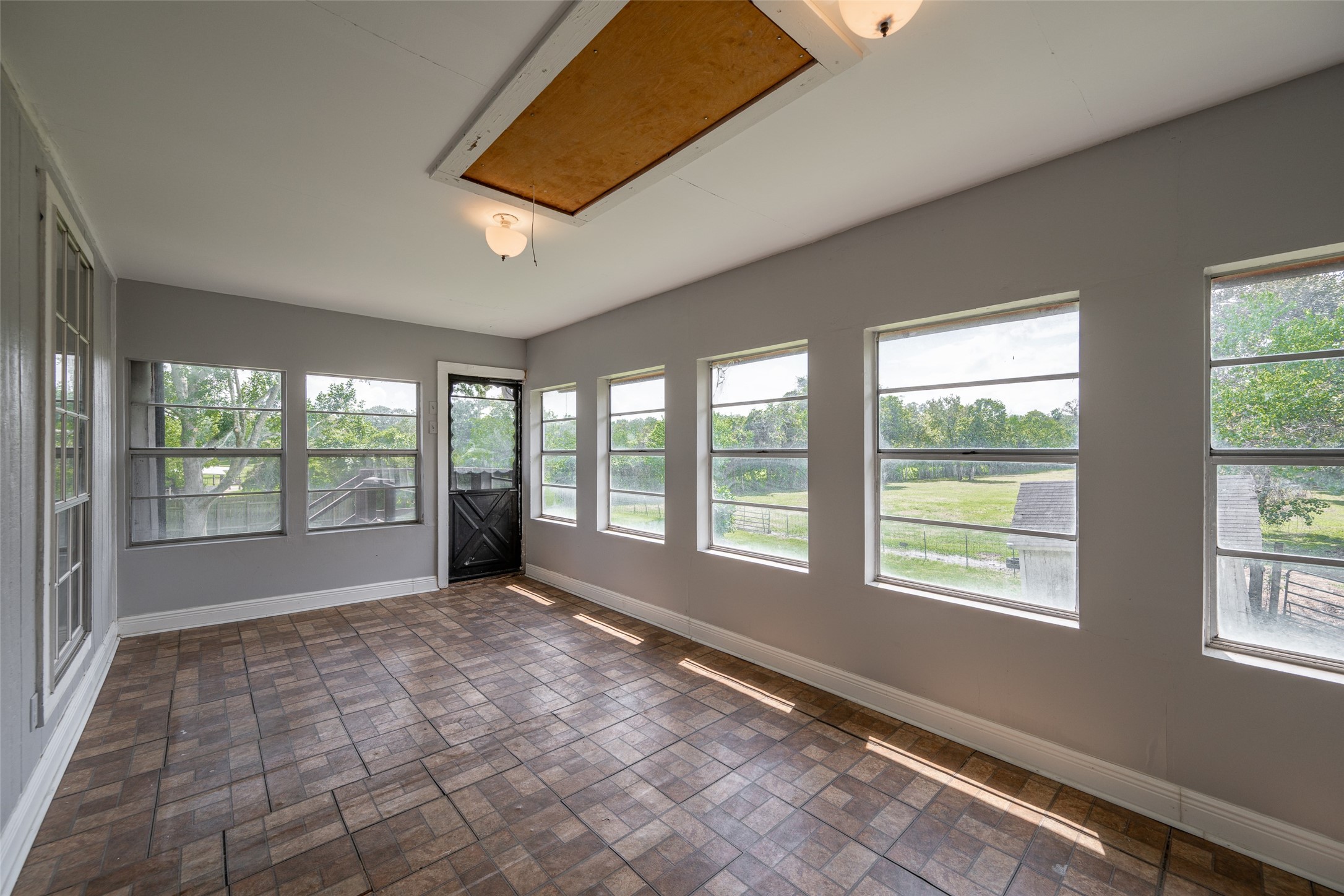 Experience relaxation in this inviting sunroom, featuring elegant wood beams, a cozy brick fireplace, and abundant natural light through large windows. Perfect for unwinding and enjoying serene views.