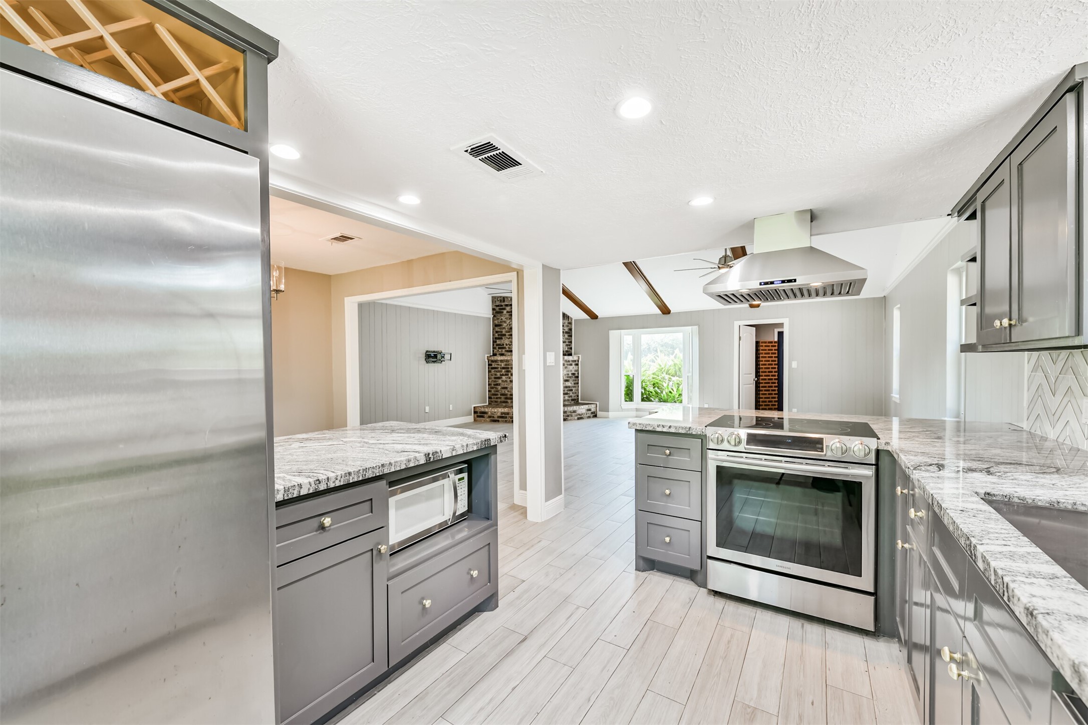 Modern kitchen featuring sleek granite countertops, stainless steel appliances, and ample cabinetry, seamlessly connecting to an inviting living area.