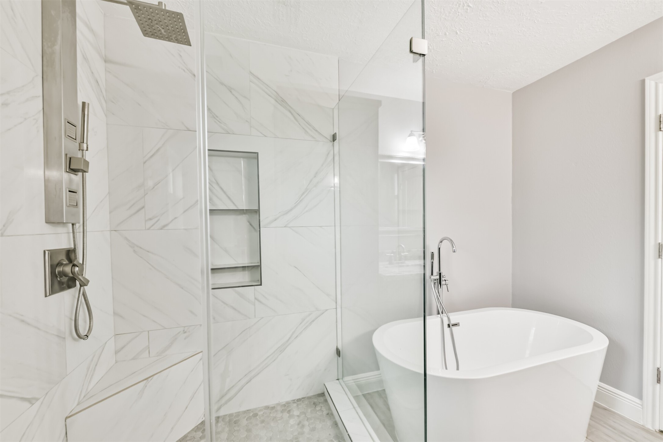 Luxurious primary bath featuring a sleek glass-enclosed shower, elegant marble tiles, and a modern freestanding tub for ultimate relaxation.