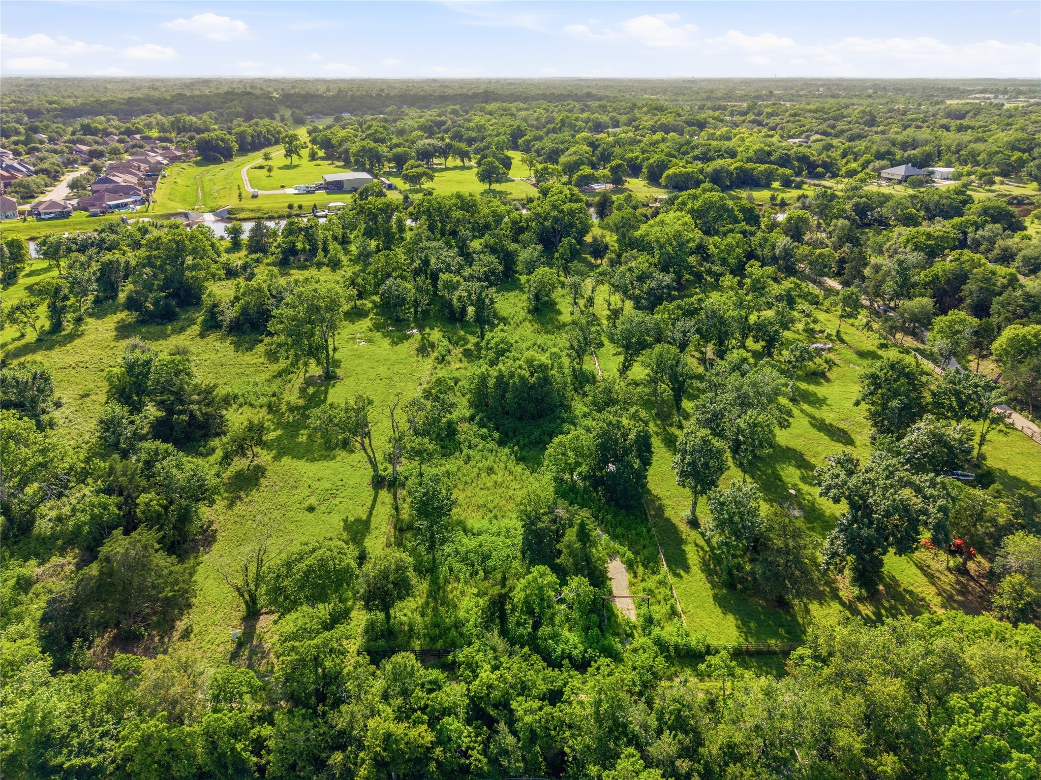This aerial photo showcases a lush, green landscape with scattered trees and open grassy areas.