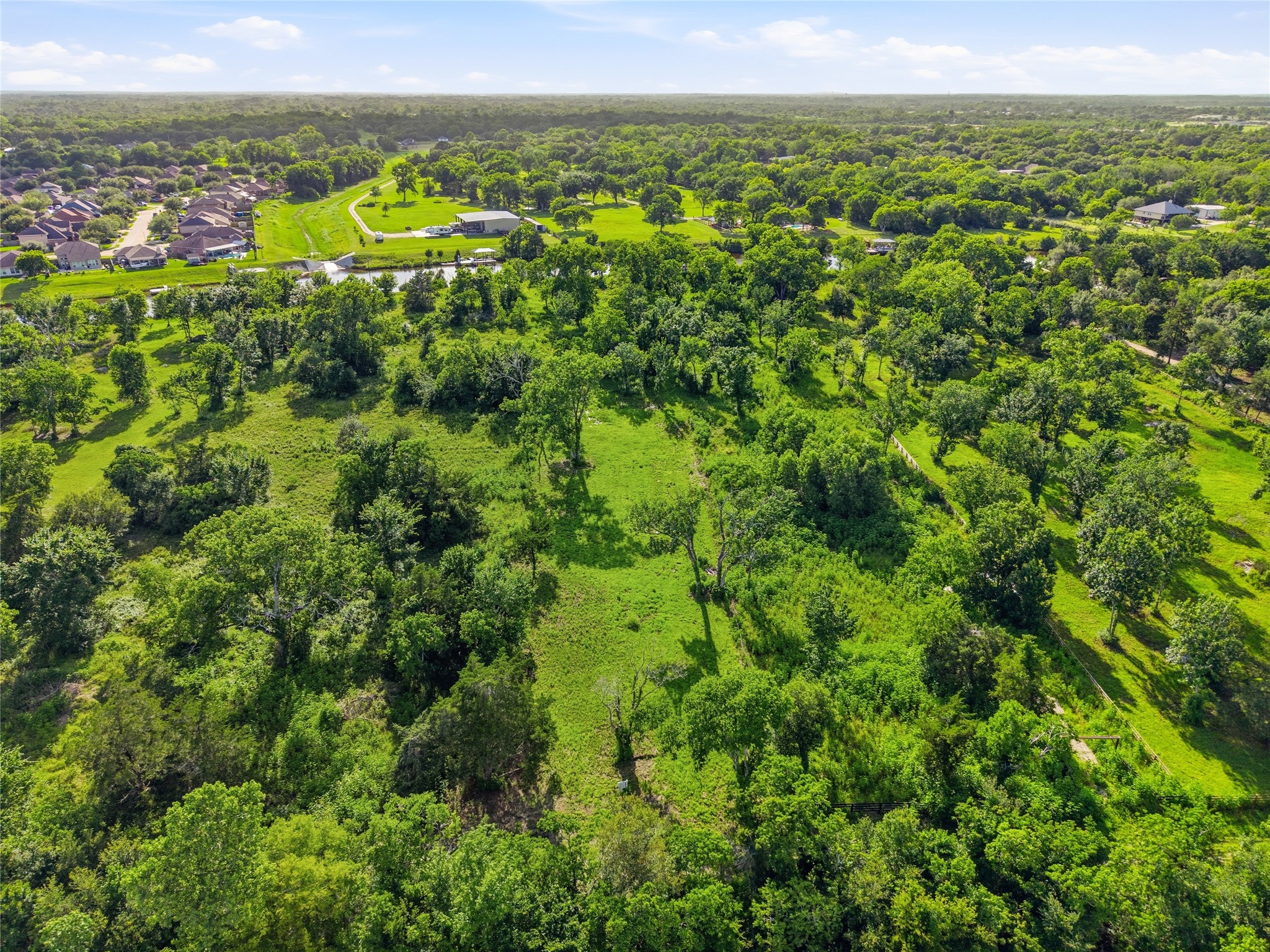 This aerial photo showcases a lush, expansive green area with scattered trees, offering a serene, natural setting.