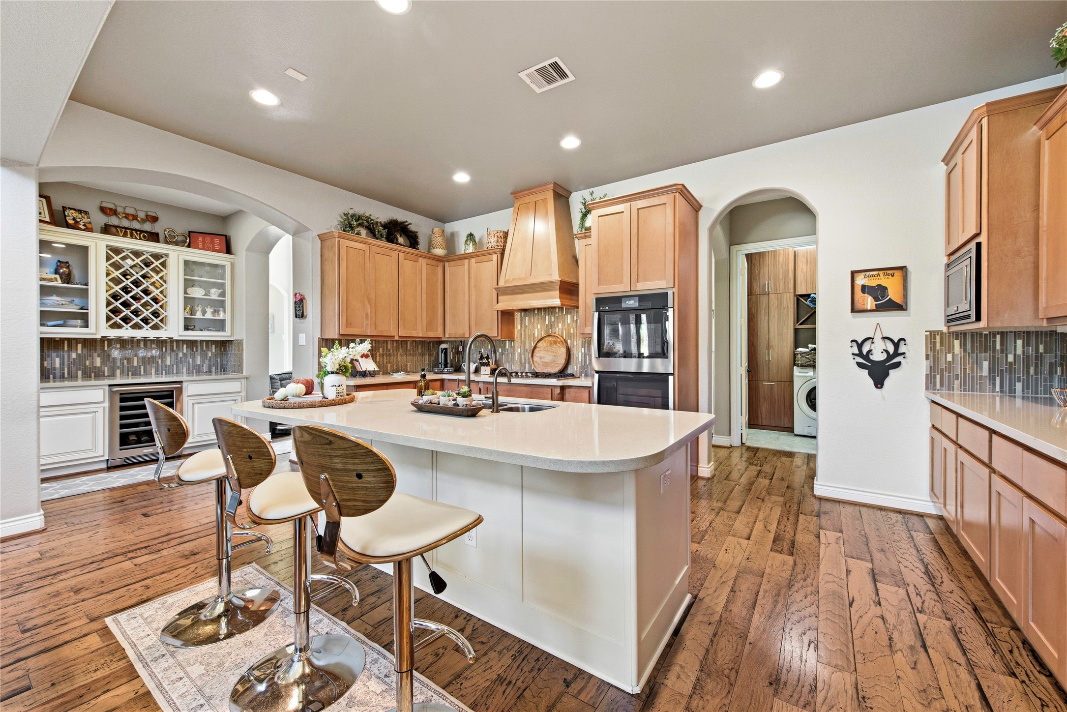 Kitchen and breakfast area featuring warm wood cabinetry, island seating and hardwood floors.