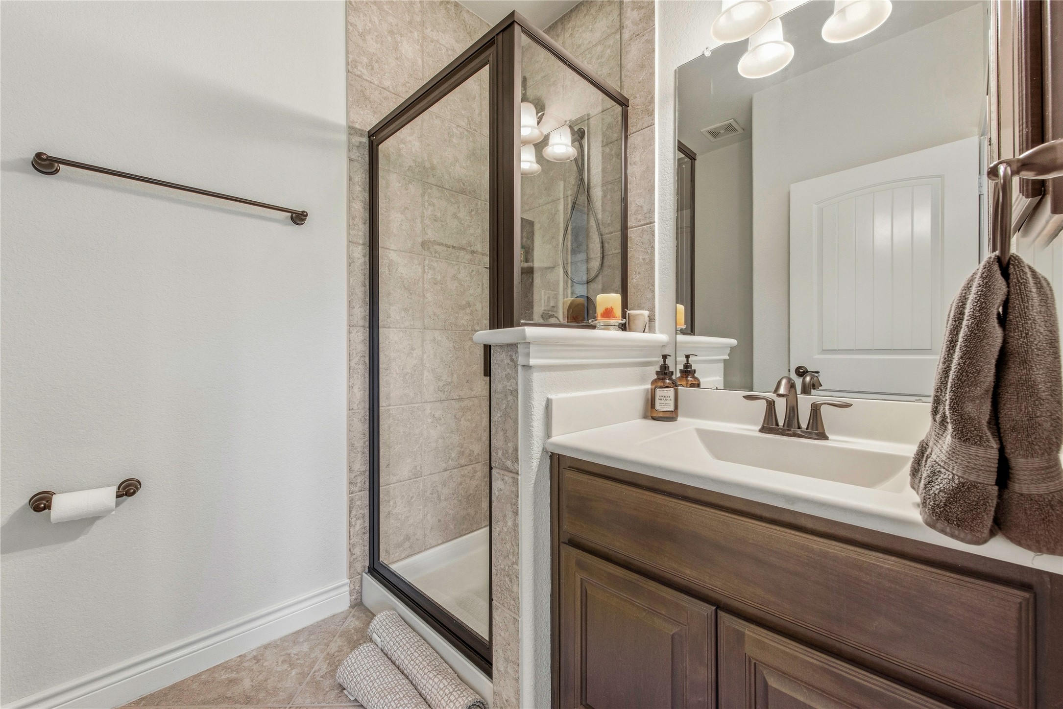 Bathroom featuring a large vanity, mirror and walk-in shower.