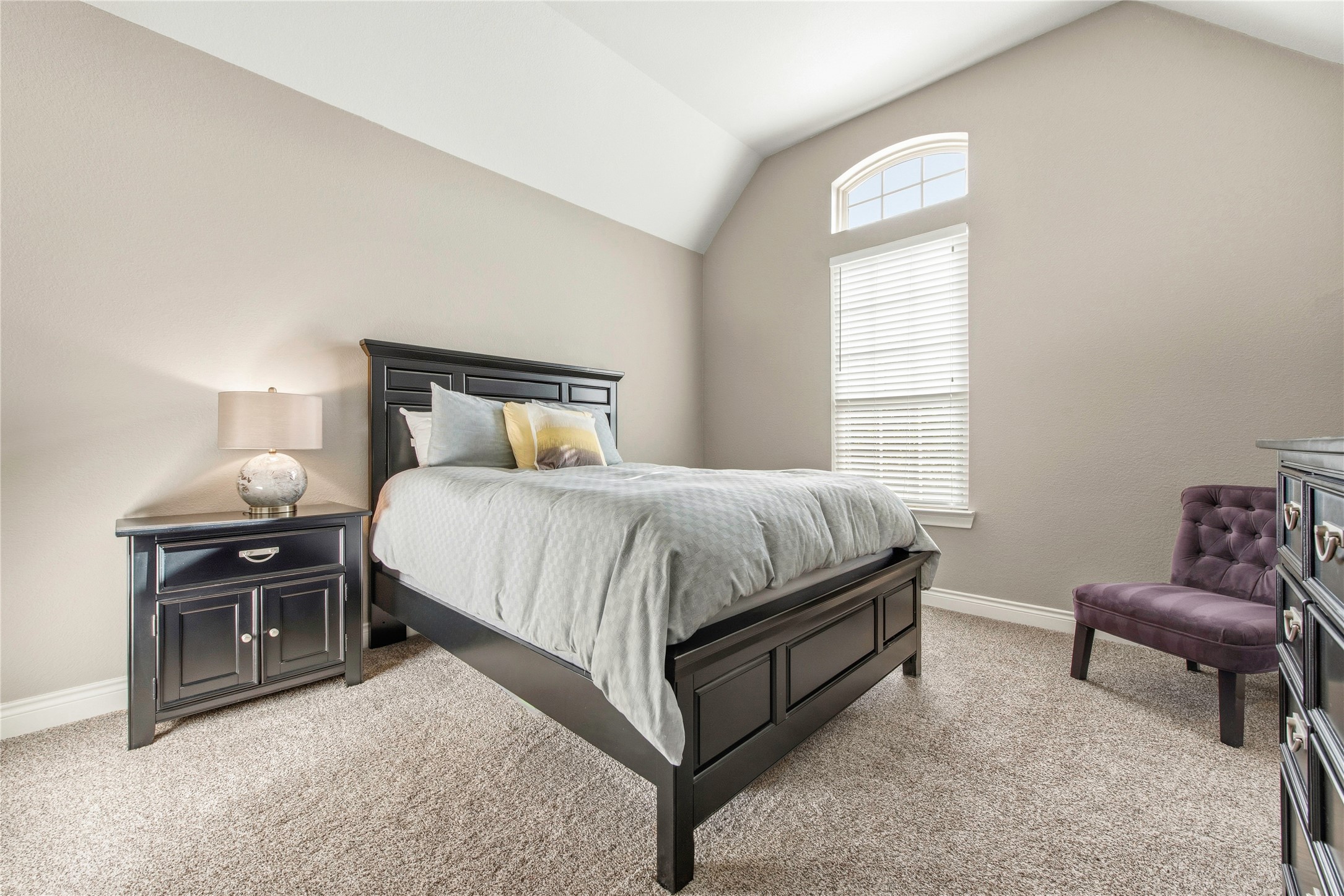 Spacious secondary bedroom featuring vaulted ceilings, hardwood flooring and natural light.
