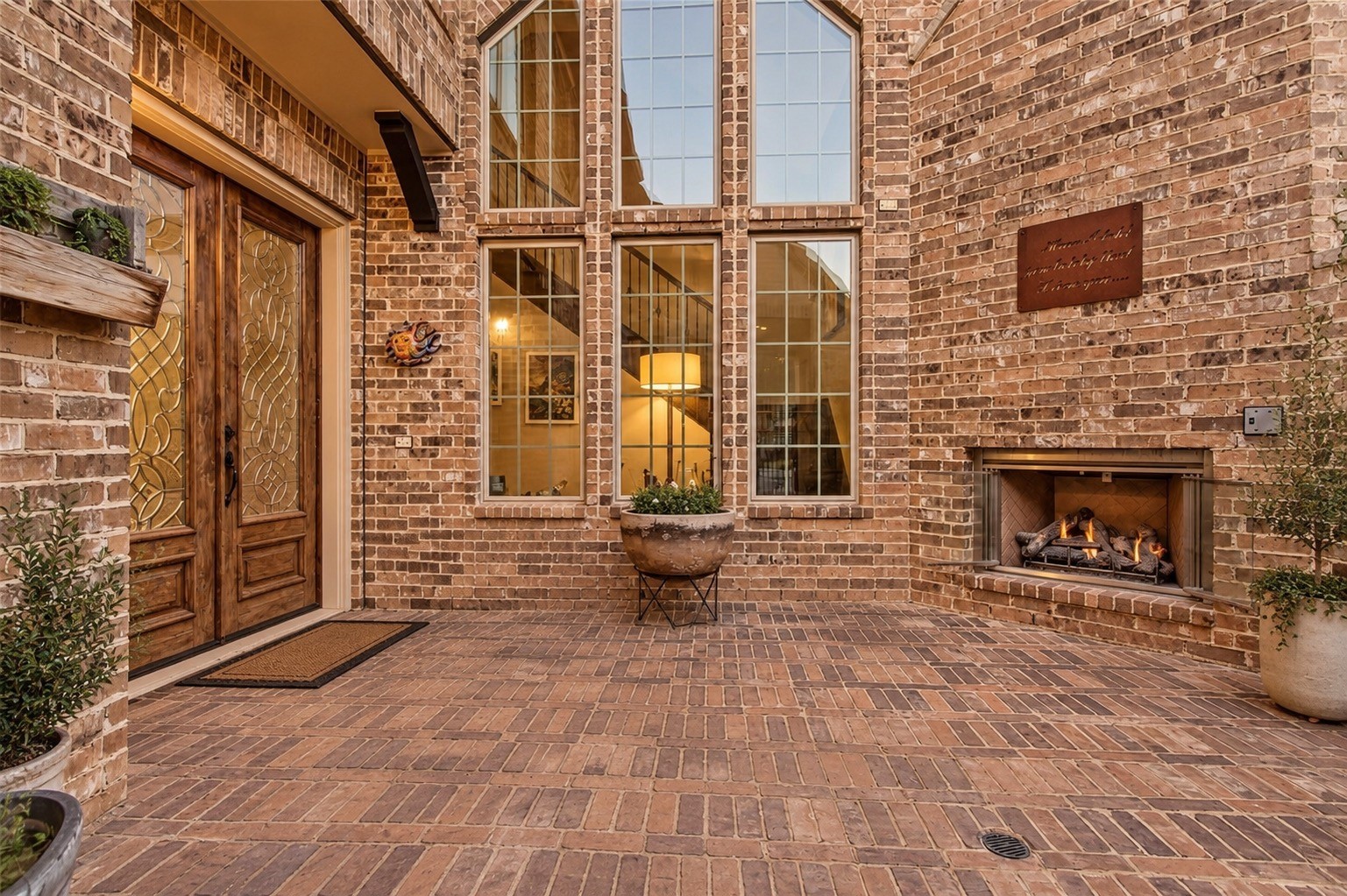 Charming courtyard entry with brick details, mature landscaping and outdoor seating area.