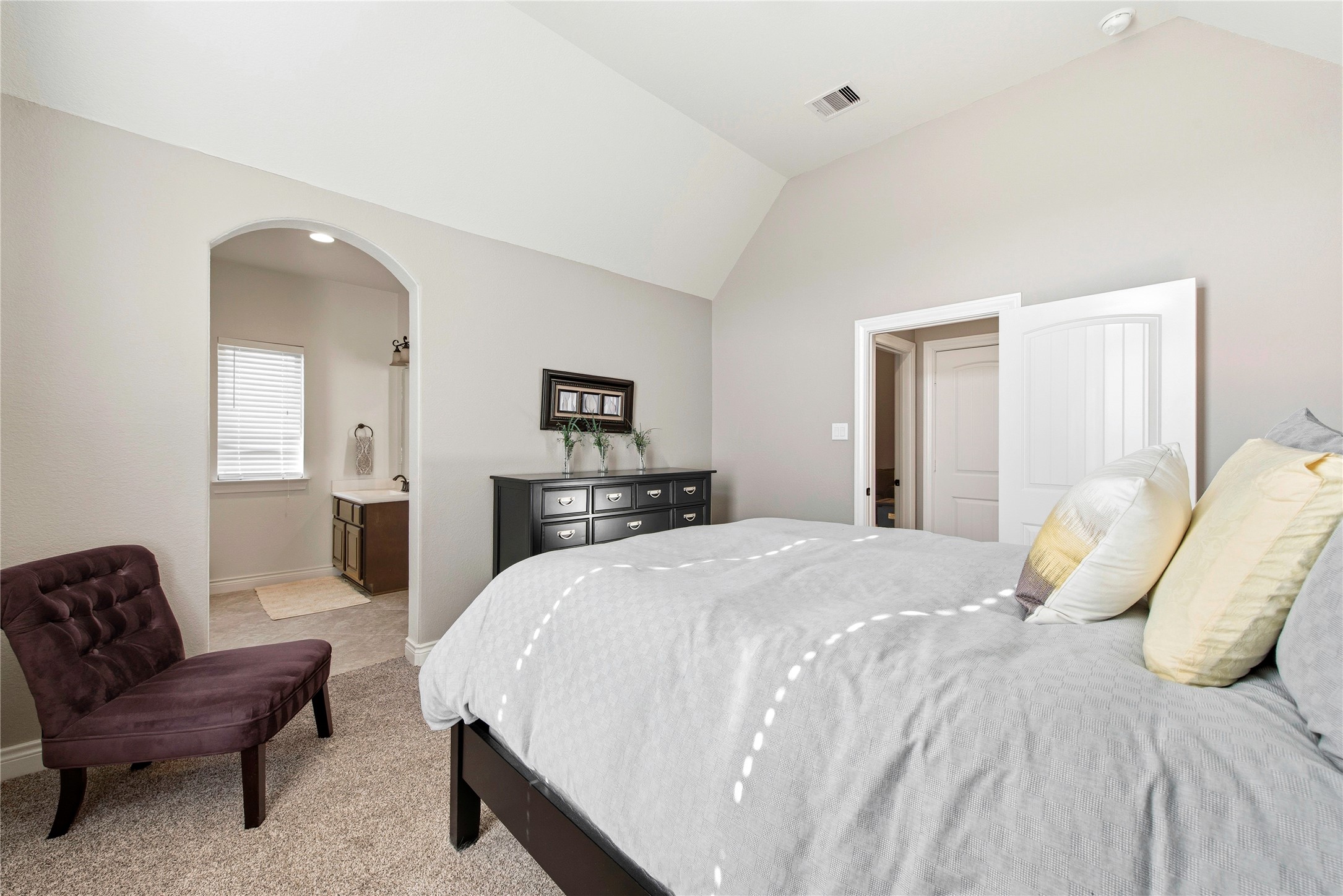 Bright bedroom featuring neutral finishes, spacious layout and comfortable seating area.