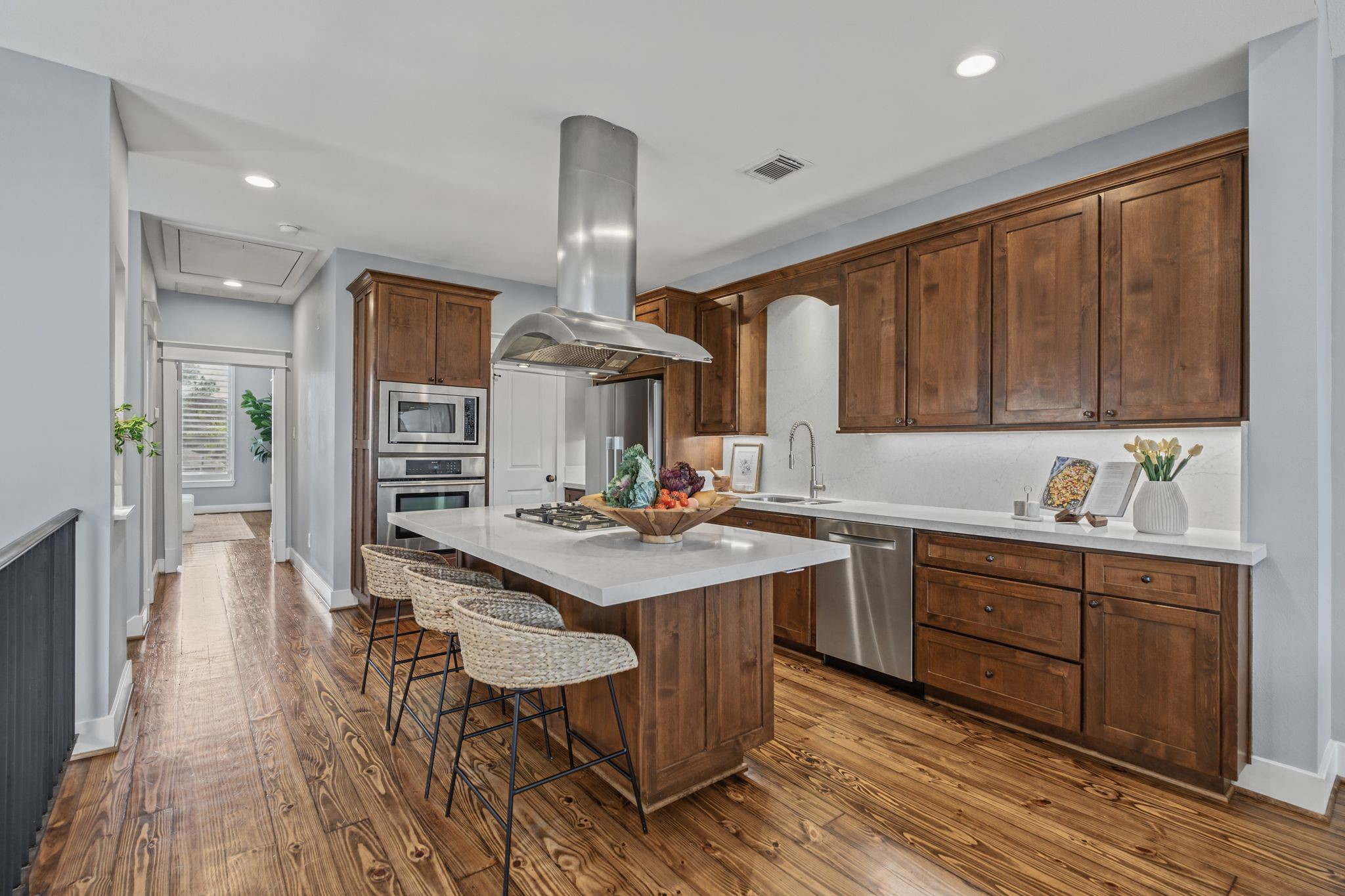 The open-concept kitchen pairs light countertops with rich wood cabinetry for a clean, contrasting look.
