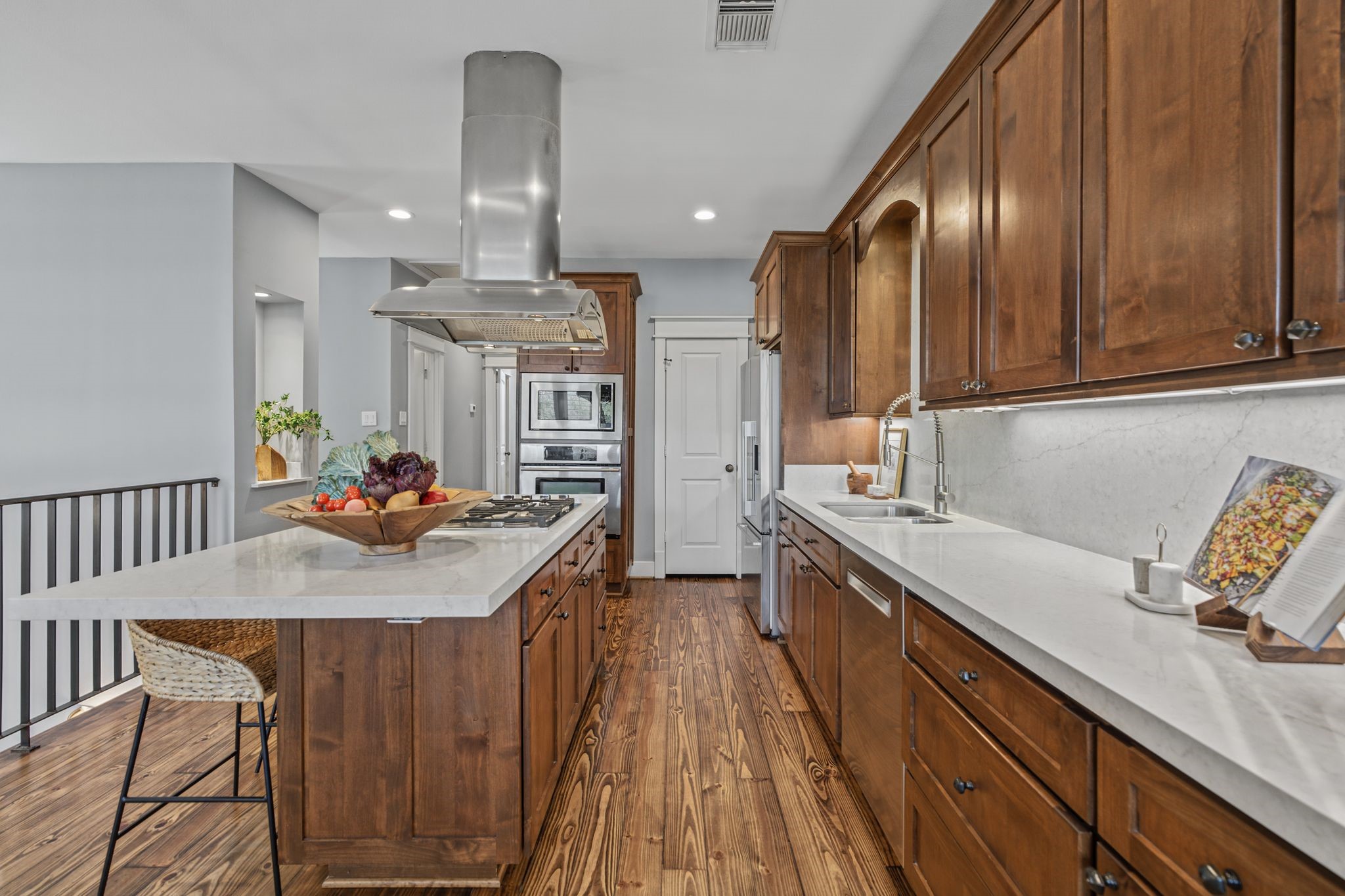 The kitchen features stainless steel appliances, a gas cooktop, a new Fisher & Paykel microwave (June 2026), and a spacious island with seating.