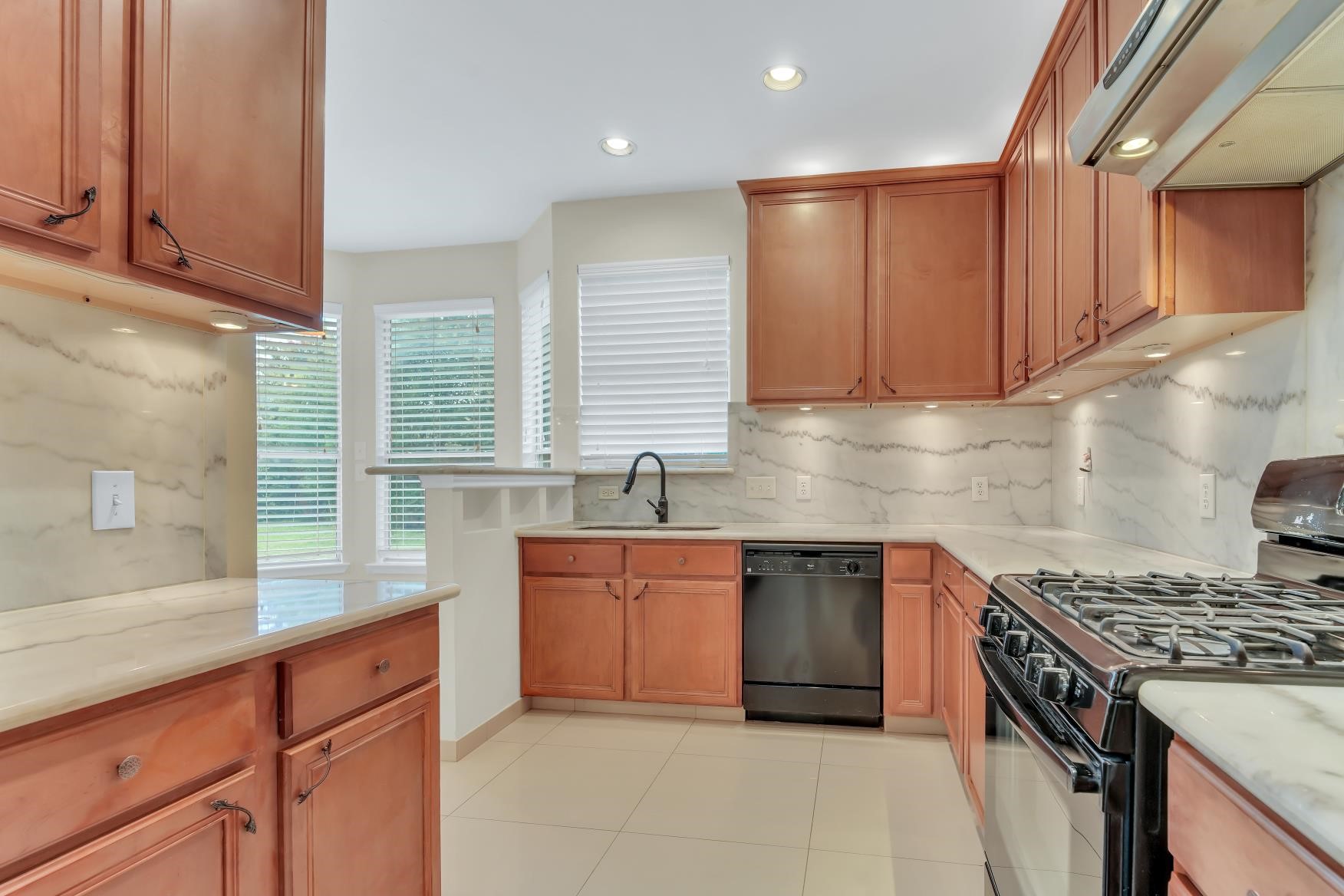 Spacious kitchen featuring a sleek gas stove and elegant granite countertops with matching backsplash