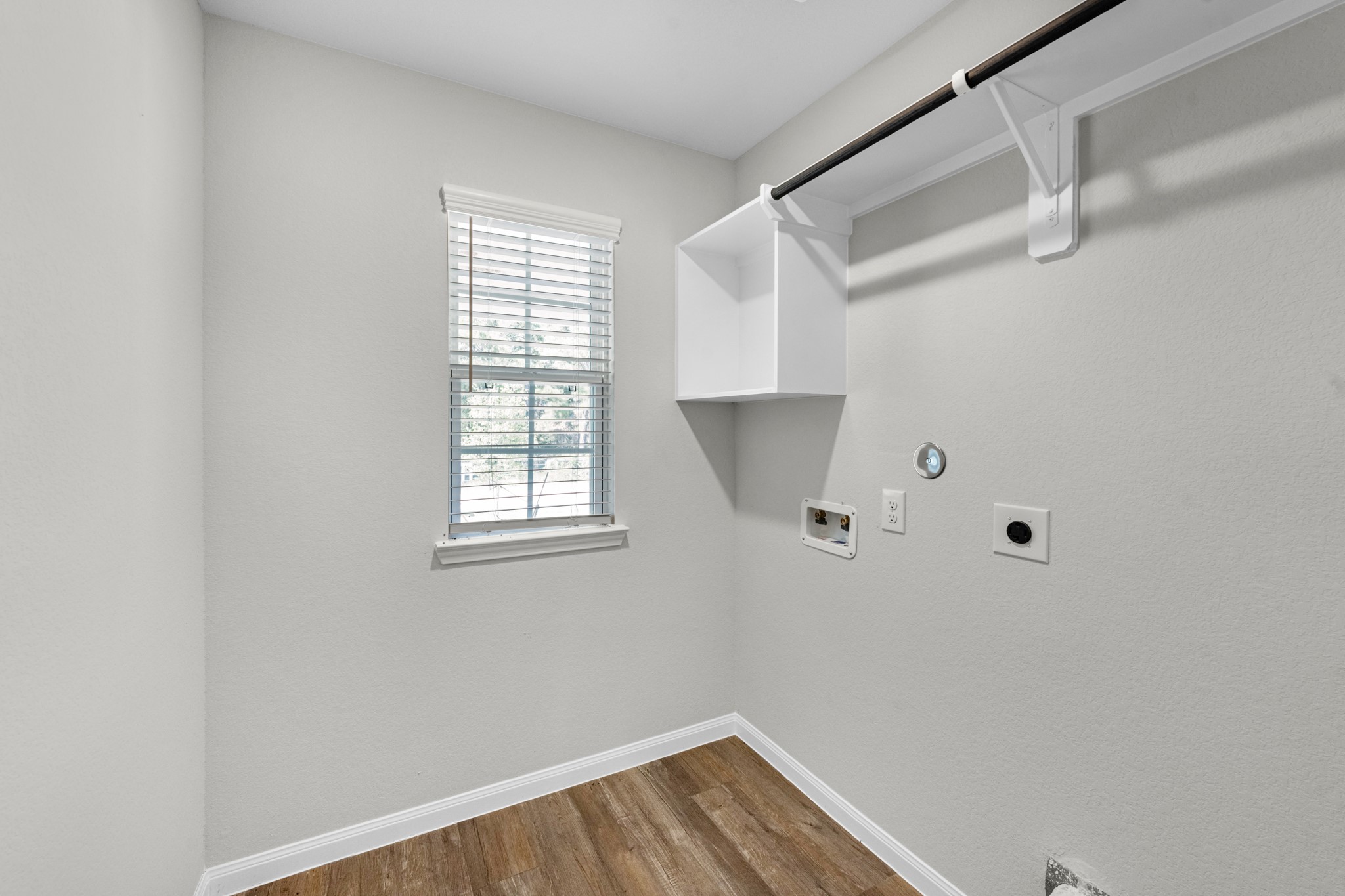 A functional laundry in the home includes a storage nook, shelf, and hanging rack.