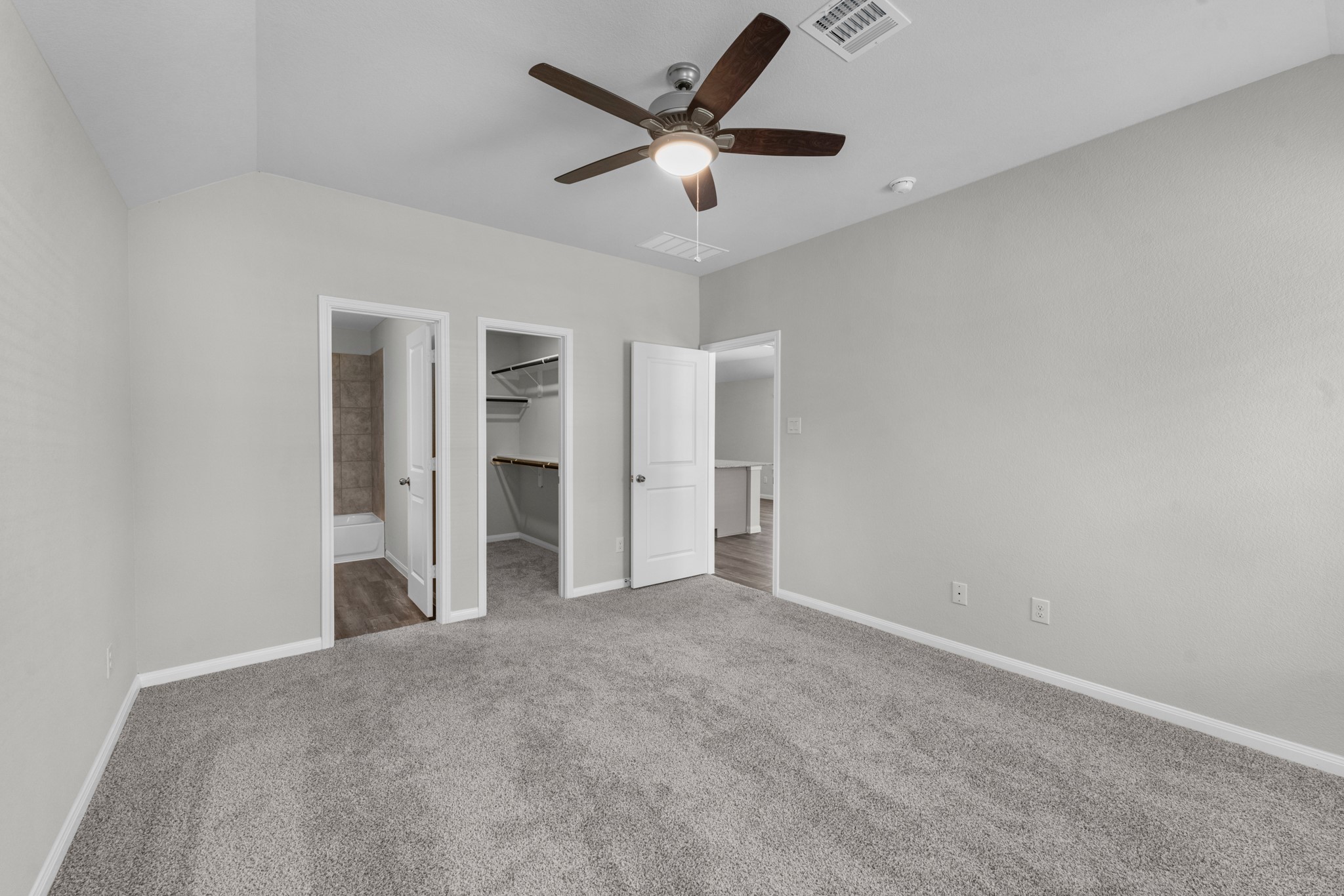 Additional view of the primary bedroom showing the en suite bathroom and walk in closet.