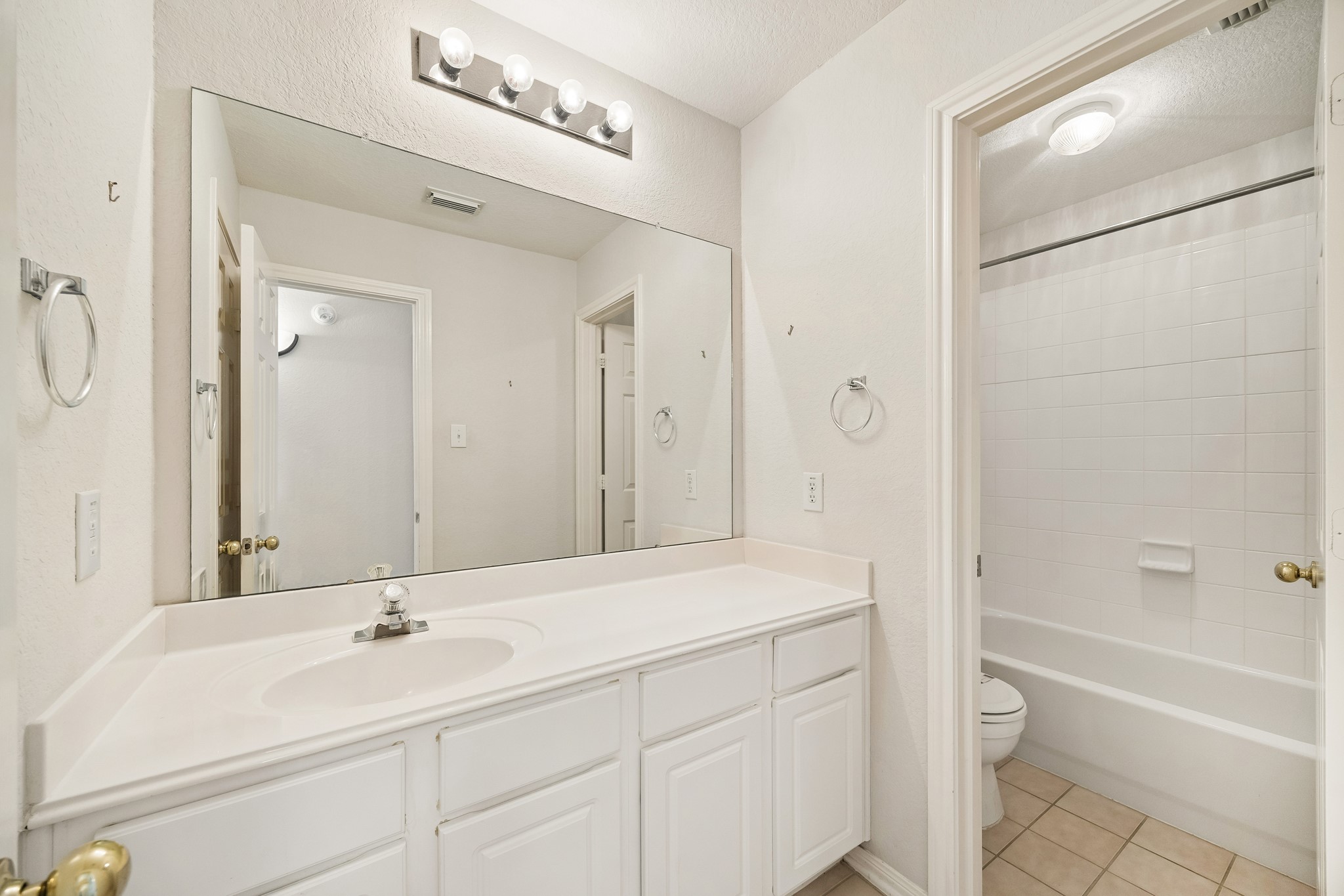 The upstairs guest bathroom keeps daily routines simple with a long vanity, ample counter space, bright lighting and a private water closet with a convenient tub and shower combination.