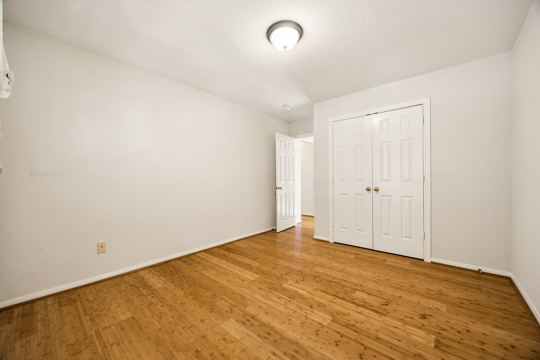 Guest bedroom number two keeps things comfortable and easy with warm bamboo flooring, a neutral color palette, a large closet and convenient access to the nearby full bathroom.