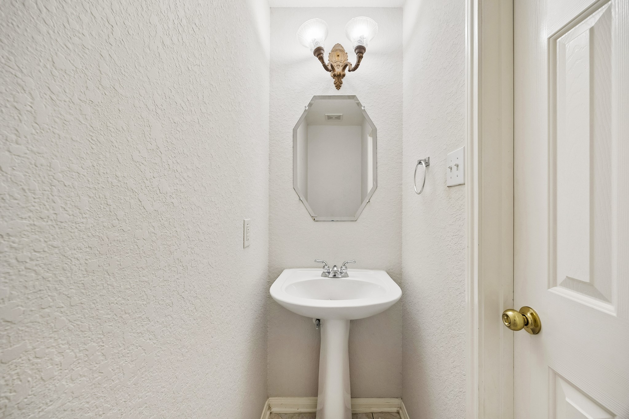 A convenient first floor powder bath is ready for guests with a classic pedestal sink, bright vanity lighting and an easy location just off the main living areas.