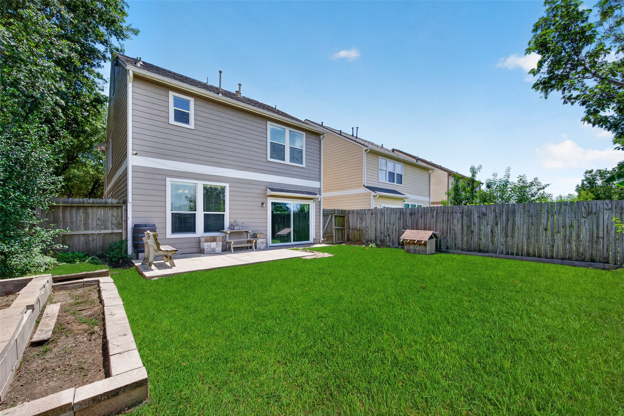 Spacious backyard with a well-maintained lawn, patio area with seating, and a wooden fence for privacy. Ideal for outdoor activities and relaxation.