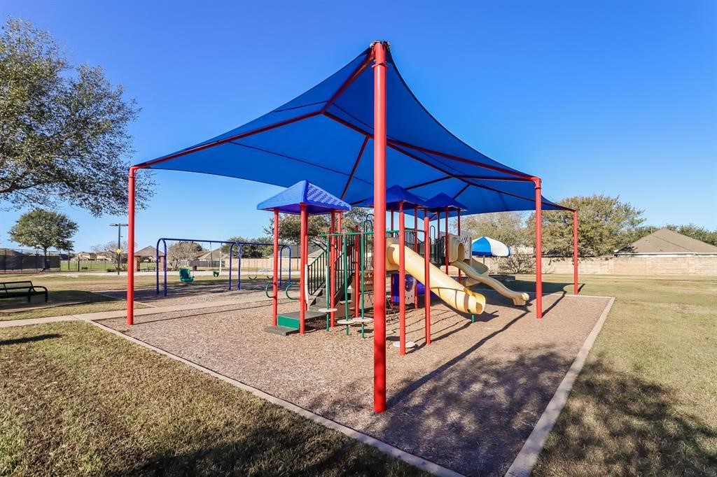 Discover the perfect family haven with a vibrant kids' play area, complete with shaded slides and swings, nestled in a spacious and sunny outdoor setting.