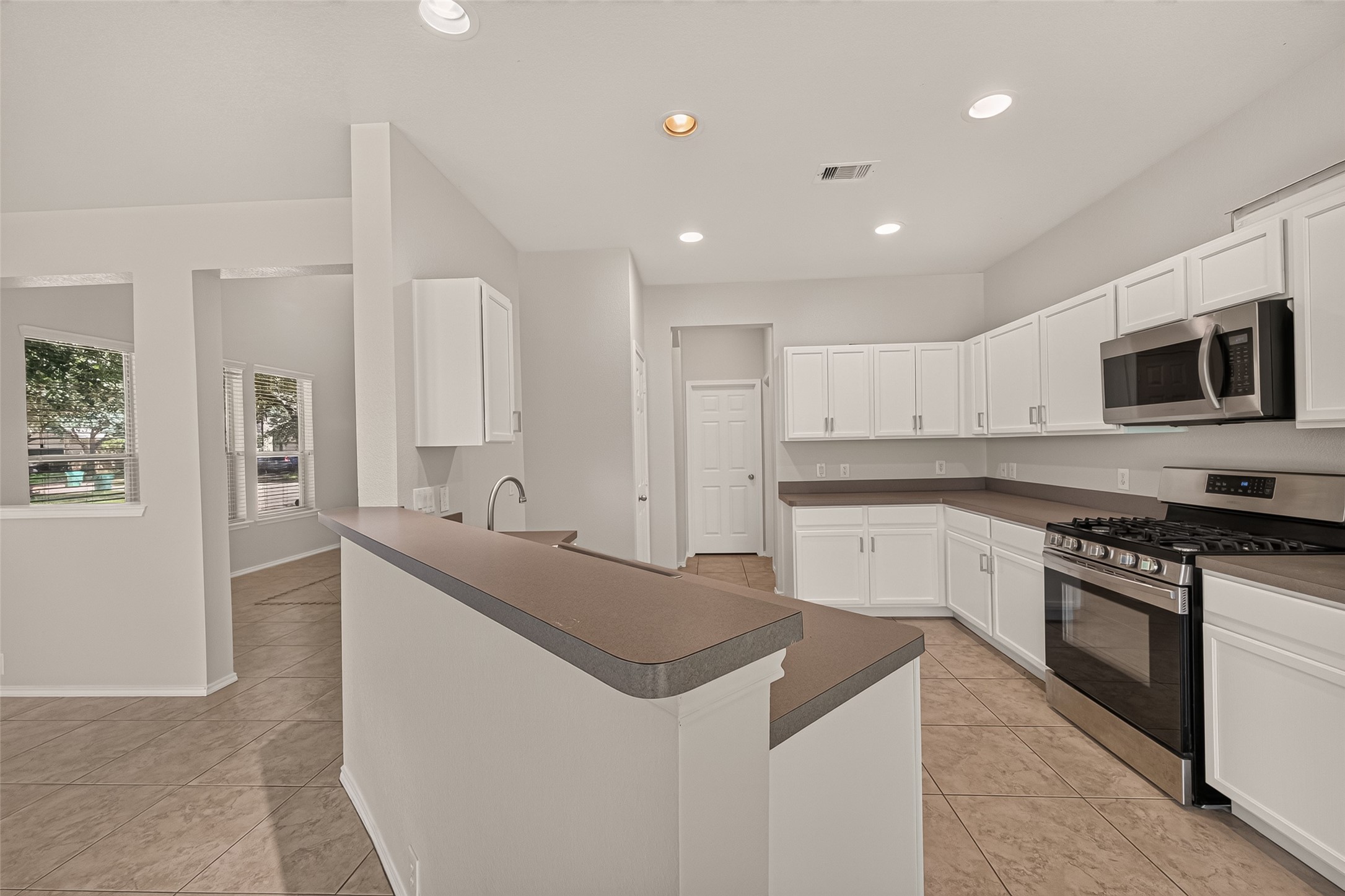 Bright, open living space with large sliding glass doors leading to a grassy backyard. Features tiled floors, a ceiling fan, and ample natural light. Perfect for indoor-outdoor living.