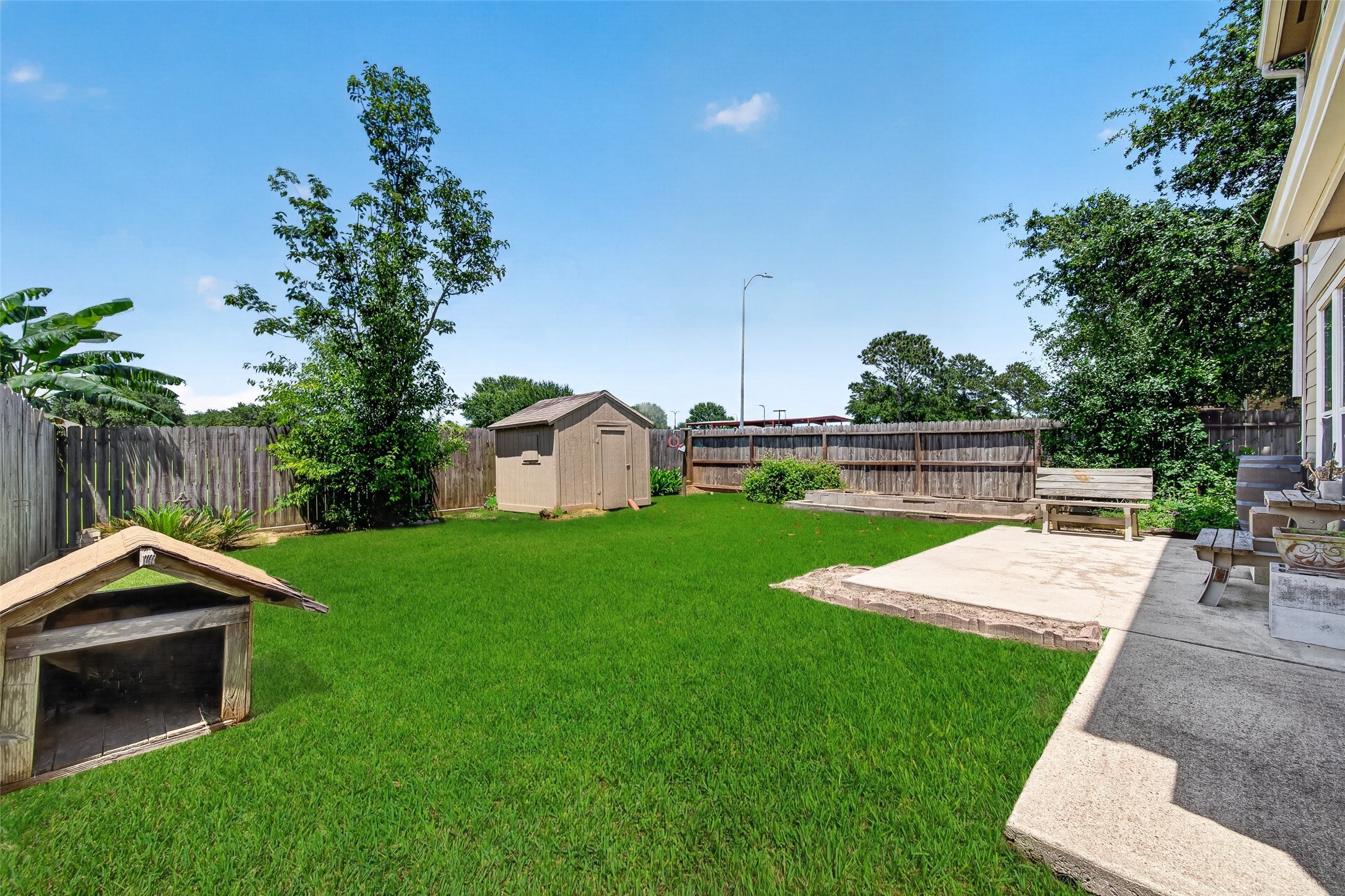Spacious backyard with a well-maintained lawn, patio area with seating, and a wooden fence for privacy. Ideal for outdoor activities and relaxation.