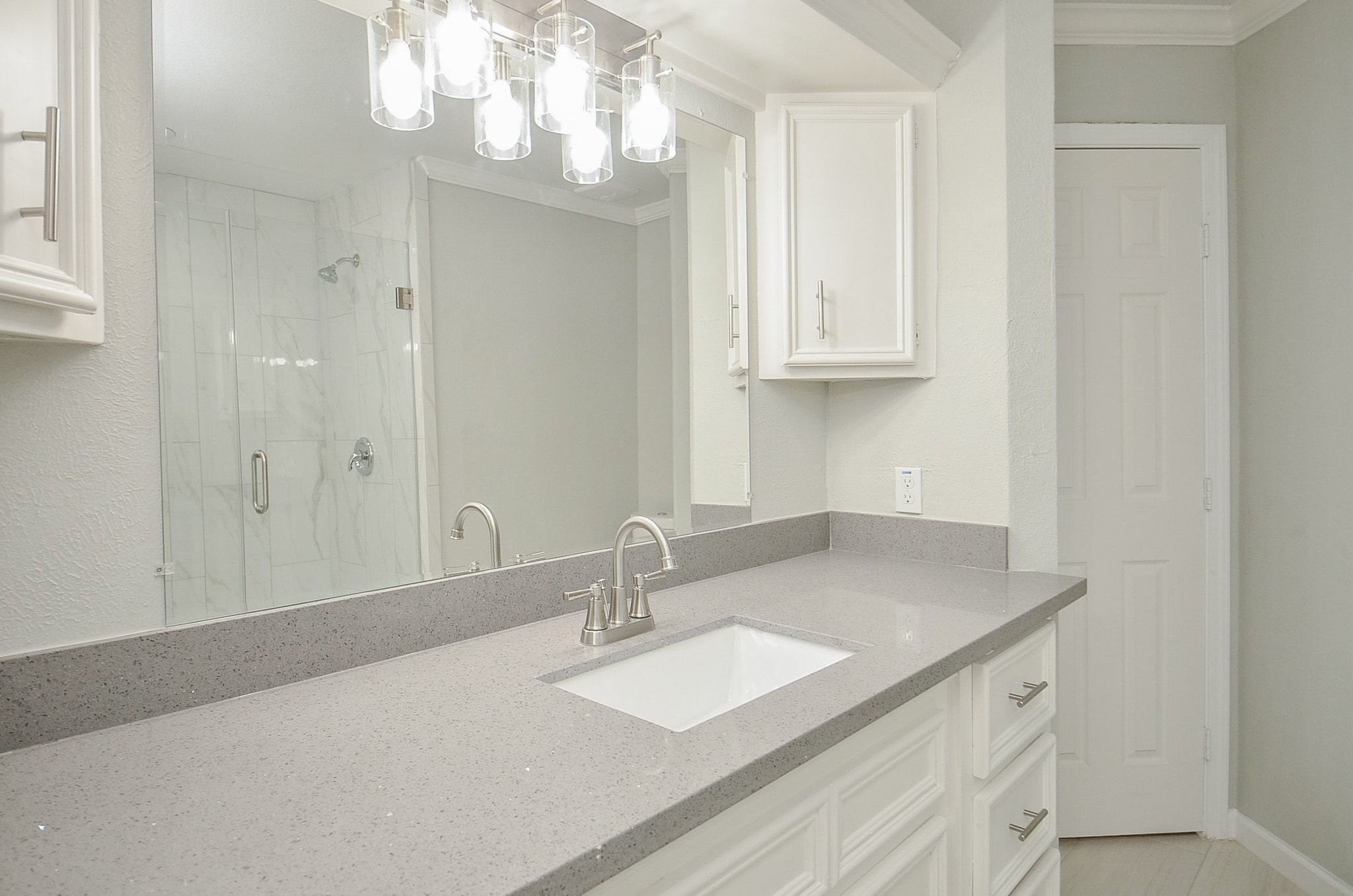 Countertops equipped with double sinks offering unlimited amounts of space. Notice the beautiful light fixture that hangs above the mirror.